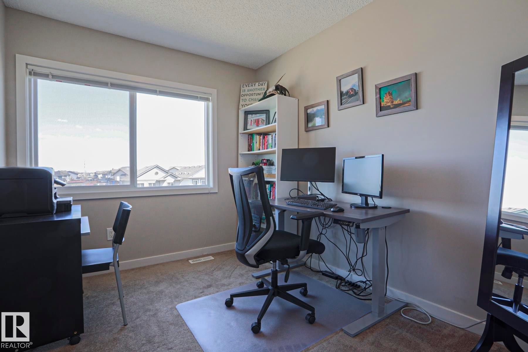 3rd bedroom used an a convenient work from home office carpeted featuring a large window with white trim, built-in shelving, and neutral wall tones - 1622 33A Street Nw, Edmonton, AB - Indoor Photo Showing Office