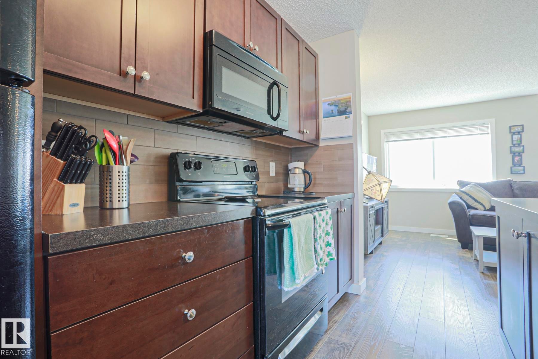 Convenient built in microwave hood fan and quartz counter tops - 1622 33A Street Nw, Edmonton, AB - Indoor Photo Showing Kitchen