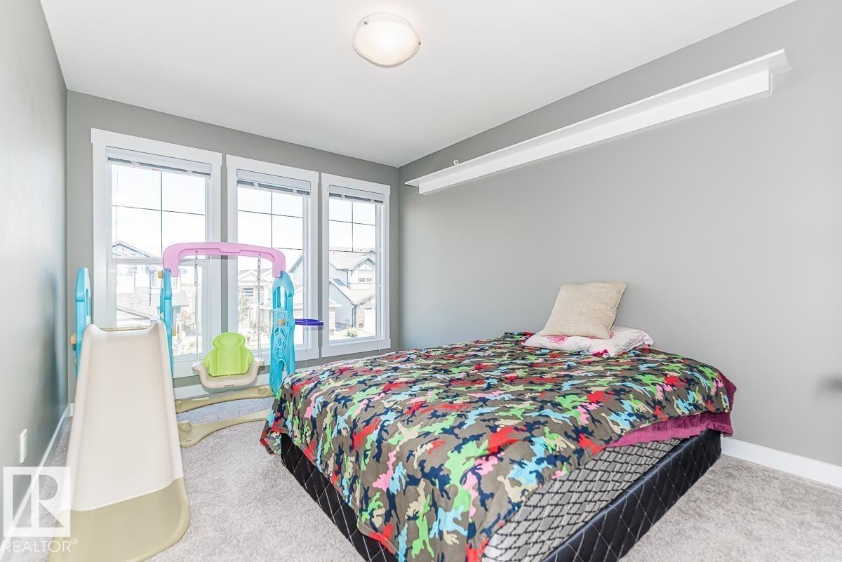 Bedroom featuring three large windows with white trim, light gray painted walls, and light-colored carpeting - 9748 205 Street, Edmonton, AB - Indoor Photo Showing Bedroom