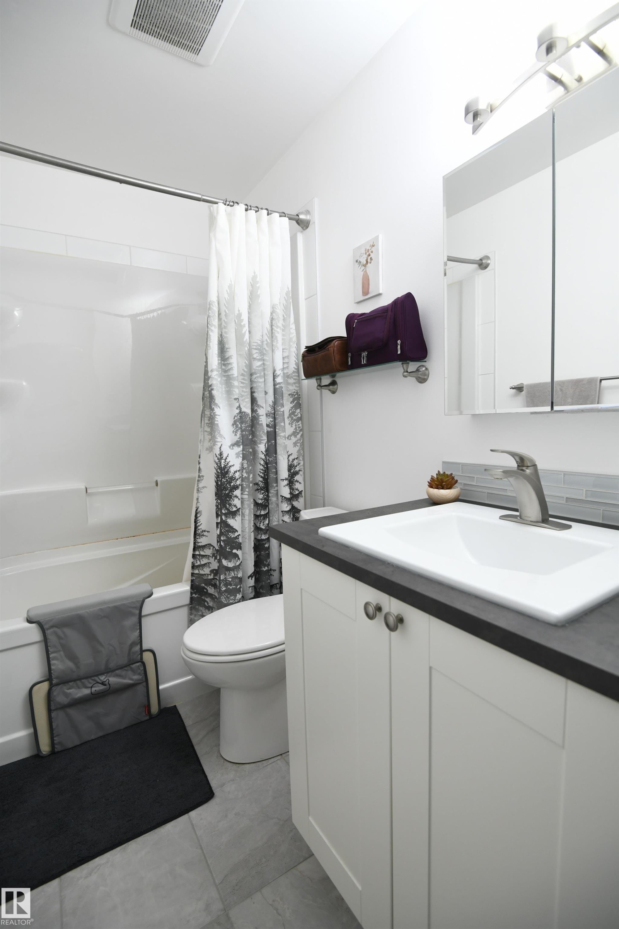 Like the kitchen, both bathrooms in the home have received a bright and contemporary renovation. The white cabinetry, new fixtures, solid surface counters, and tile accents look great - 5823 Riverbend Road, Edmonton, AB - Indoor Photo Showing Bathroom