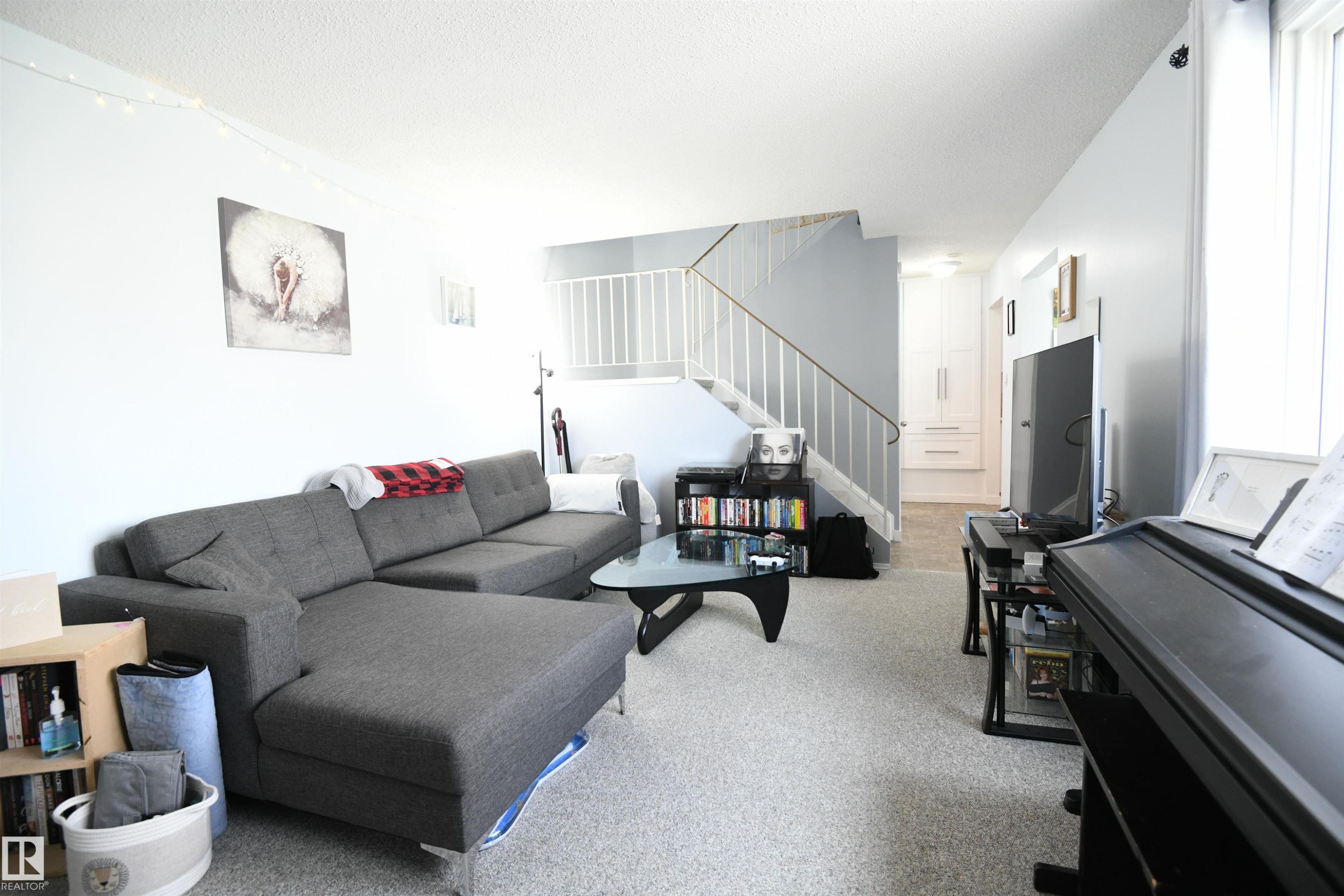 The open railings that lead upstairs to the bedroom level give an open feel to the large living room, with great furniture placement options. The kitchen and large dining area are just around the corner to the right - 5823 Riverbend Road, Edmonton, AB - Indoor