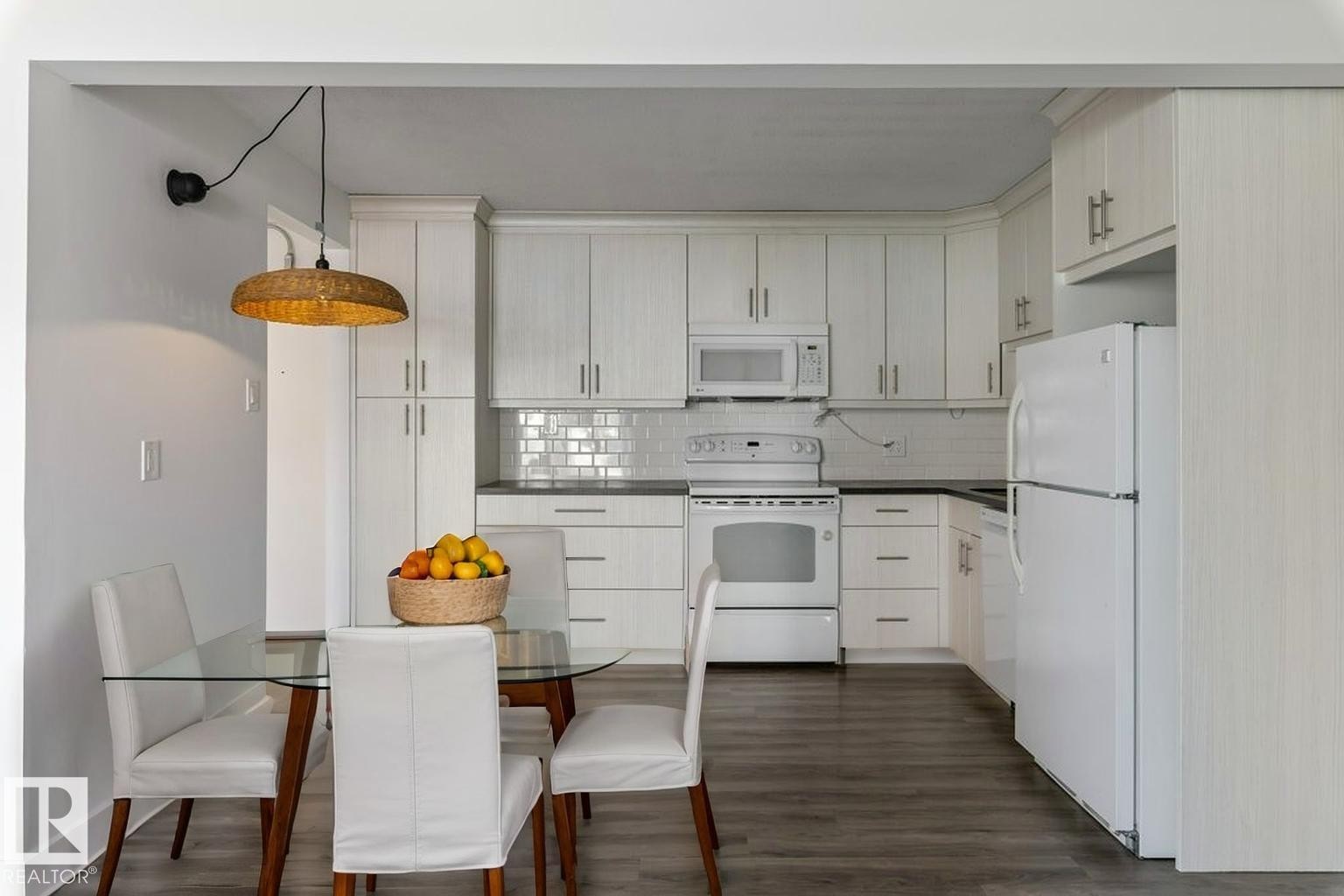 Updated Kitchen and dining area featuring amble cabinetry, subway tile backsplash & full size appliances, including a dishwasher, fridge, stove & microwave hood fan. - 101 8604 Gateway Boulevard, Edmonton, AB - Indoor Photo Showing Kitchen