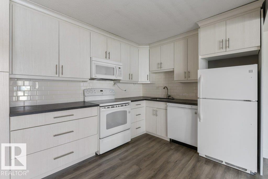 Updated Kitchen and dining area featuring amble cabinetry, subway tile backsplash & full size appliances, including a dishwasher, fridge, stove & microwave hood fan. - 101 8604 Gateway Boulevard, Edmonton, AB - Indoor Photo Showing Kitchen