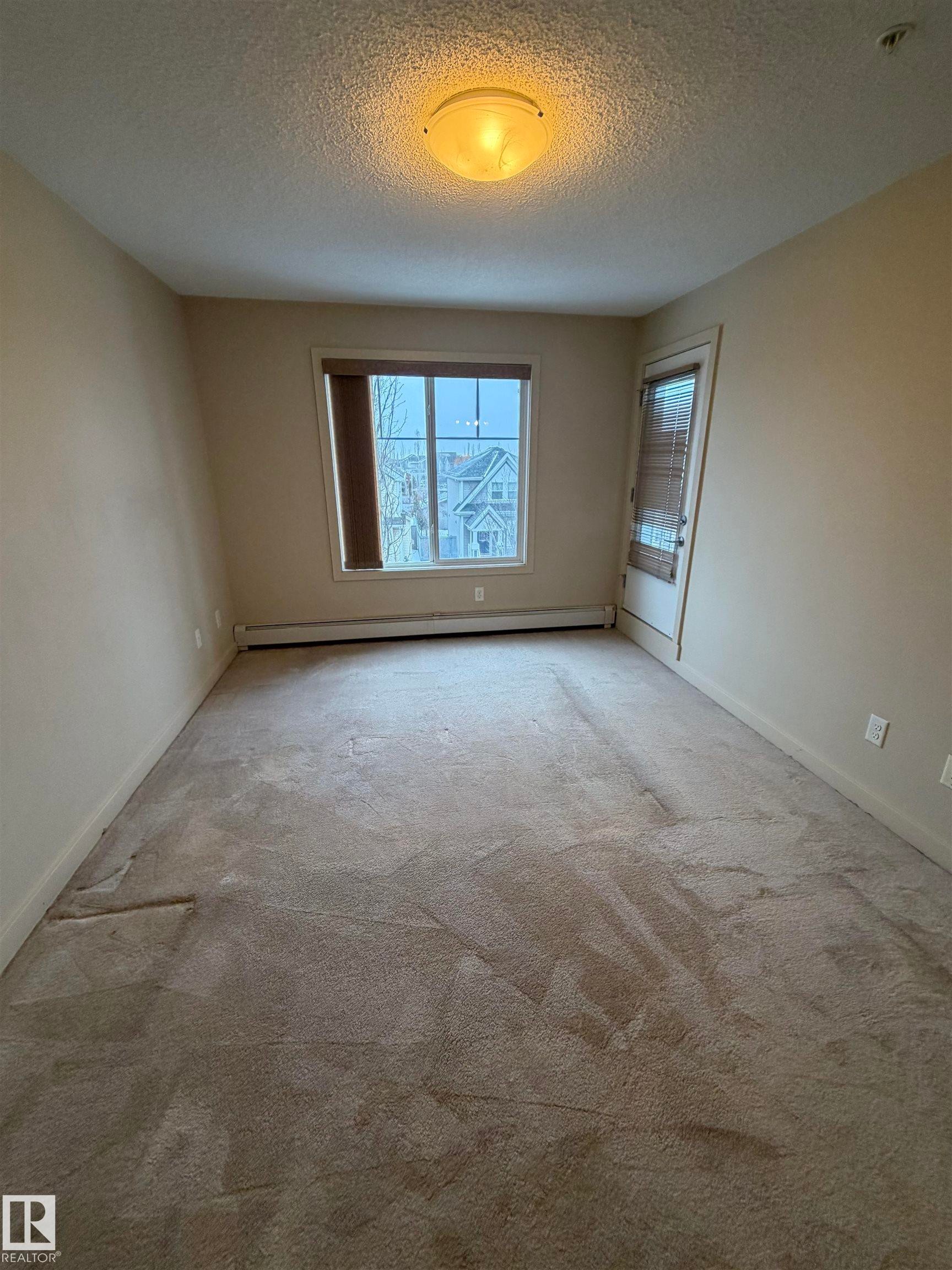 Living space with neutral-toned walls, carpet flooring, a window providing natural light, and a ceiling-mounted light fixture - 313 6084 Stanton Drive, Edmonton, AB - Indoor Photo Showing Other Room