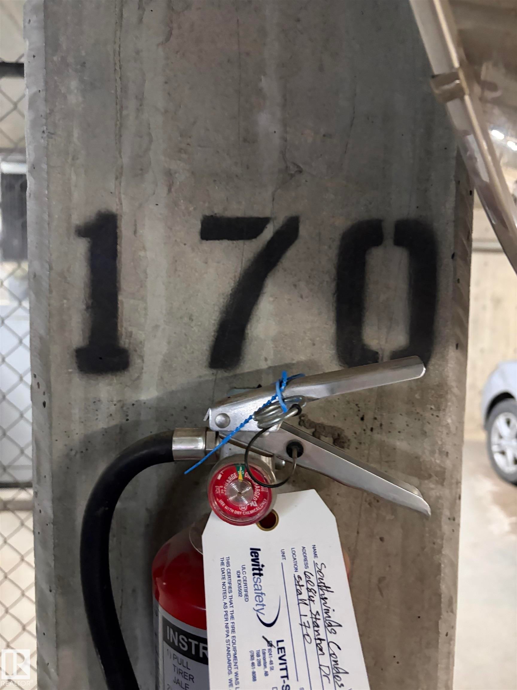 The property features a concrete support column with a stenciled "170" and a mounted fire extinguisher, visible within a garage or parking structure - 313 6084 Stanton Drive, Edmonton, AB - Indoor