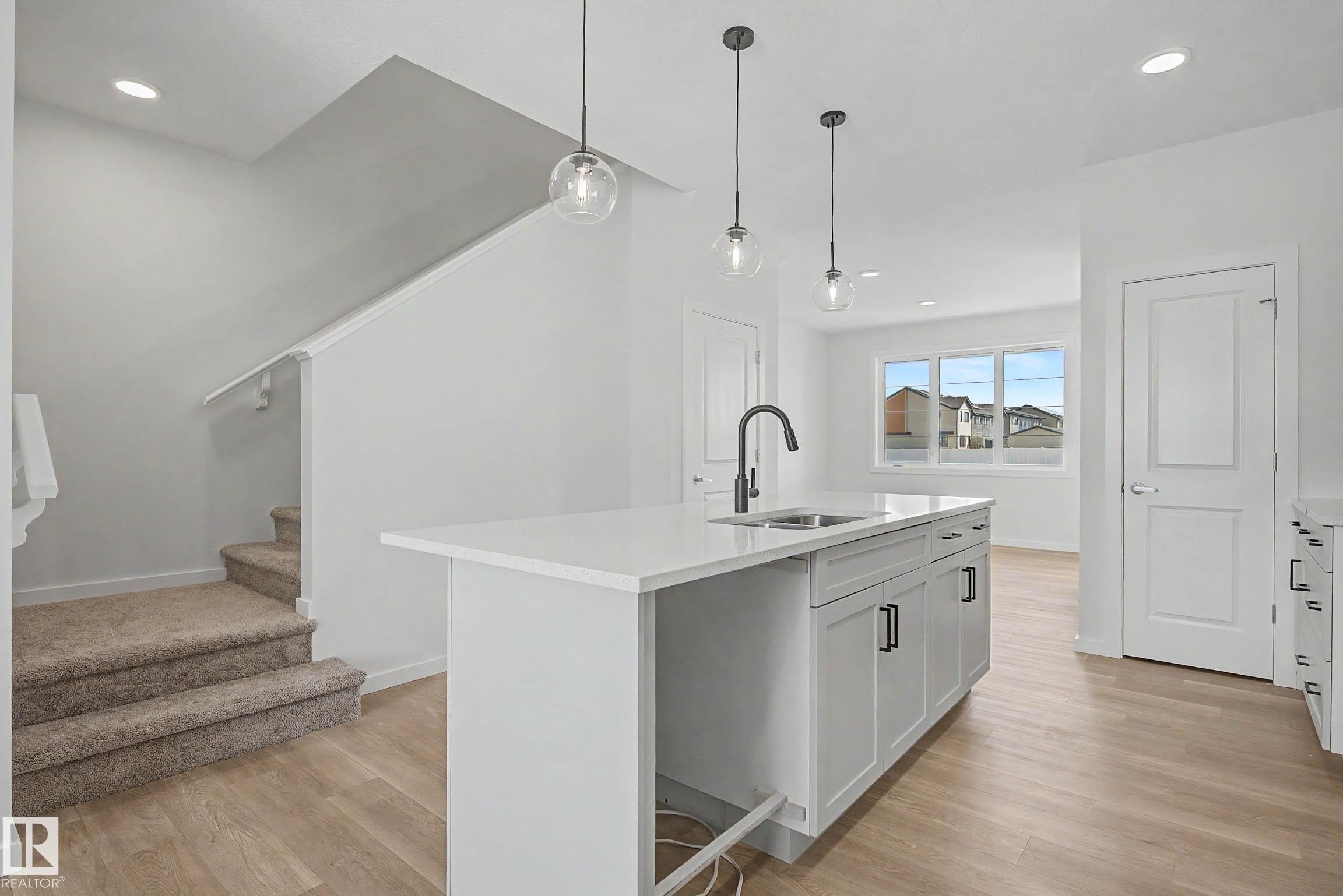 Kitchen island featuring an undermount sink, matte black faucet, and pendant lighting - 720 Southfork Drive, Leduc, AB - Indoor Photo Showing Kitchen With Upgraded Kitchen