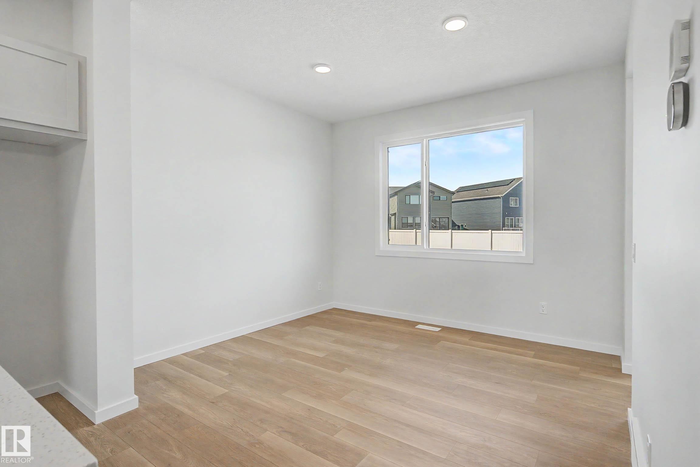 Bright interior space featuring a large window, light wood-finish flooring, recessed lighting, and crisp white walls - 720 Southfork Drive, Leduc, AB - Indoor Photo Showing Other Room