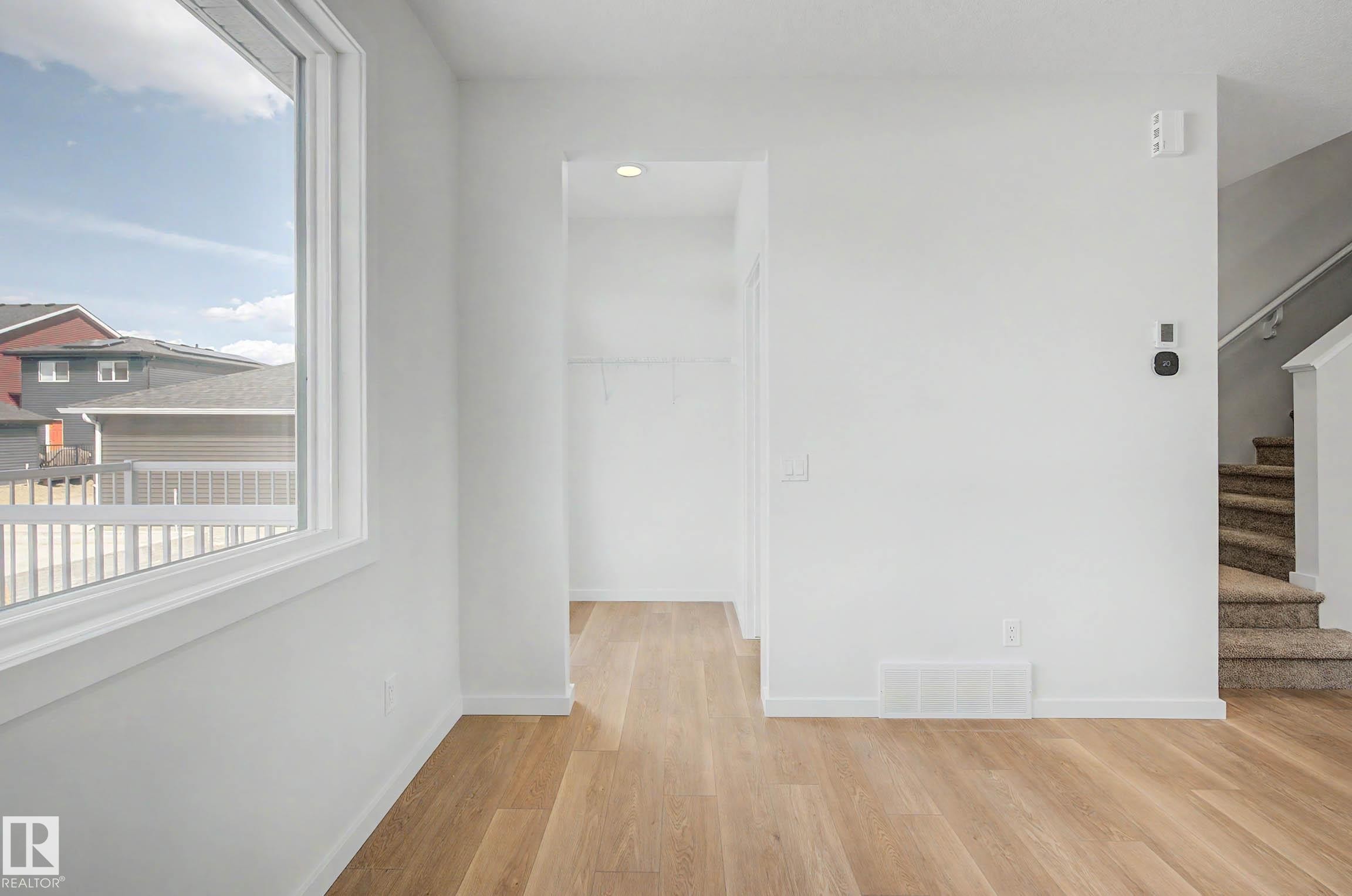 Bright interior featuring wood-finish flooring and crisp white walls - 720 Southfork Drive, Leduc, AB - Indoor Photo Showing Other Room