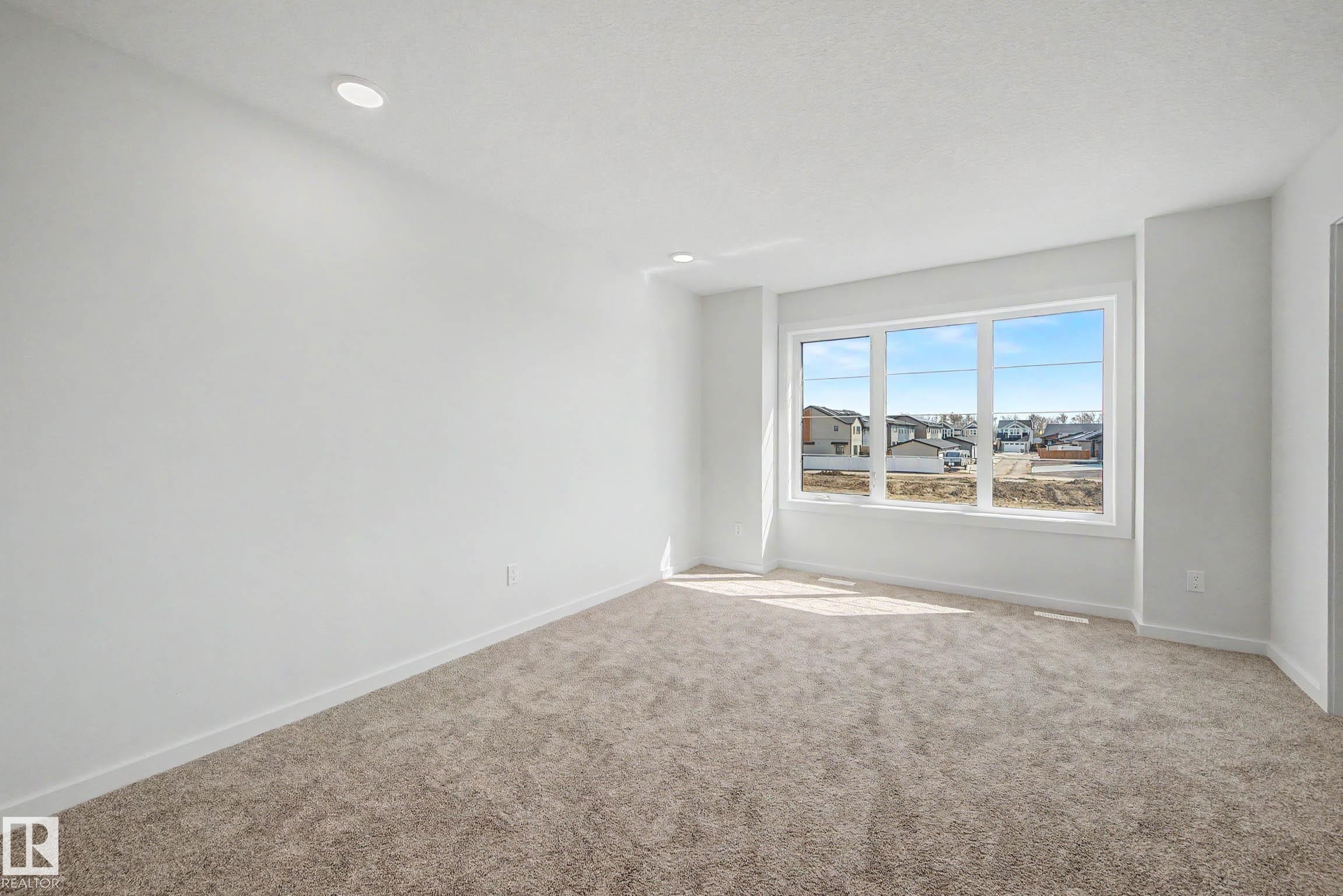 Spacious room featuring neutral carpeting, white walls, and recessed lighting - 720 Southfork Drive, Leduc, AB - Indoor Photo Showing Other Room