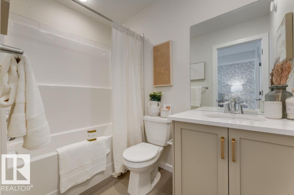 Bathroom featuring a white integrated tub and shower unit, a toilet, and a vanity with a white countertop and light-toned cabinetry - 720 Southfork Drive, Leduc, AB - Indoor Photo Showing Bathroom