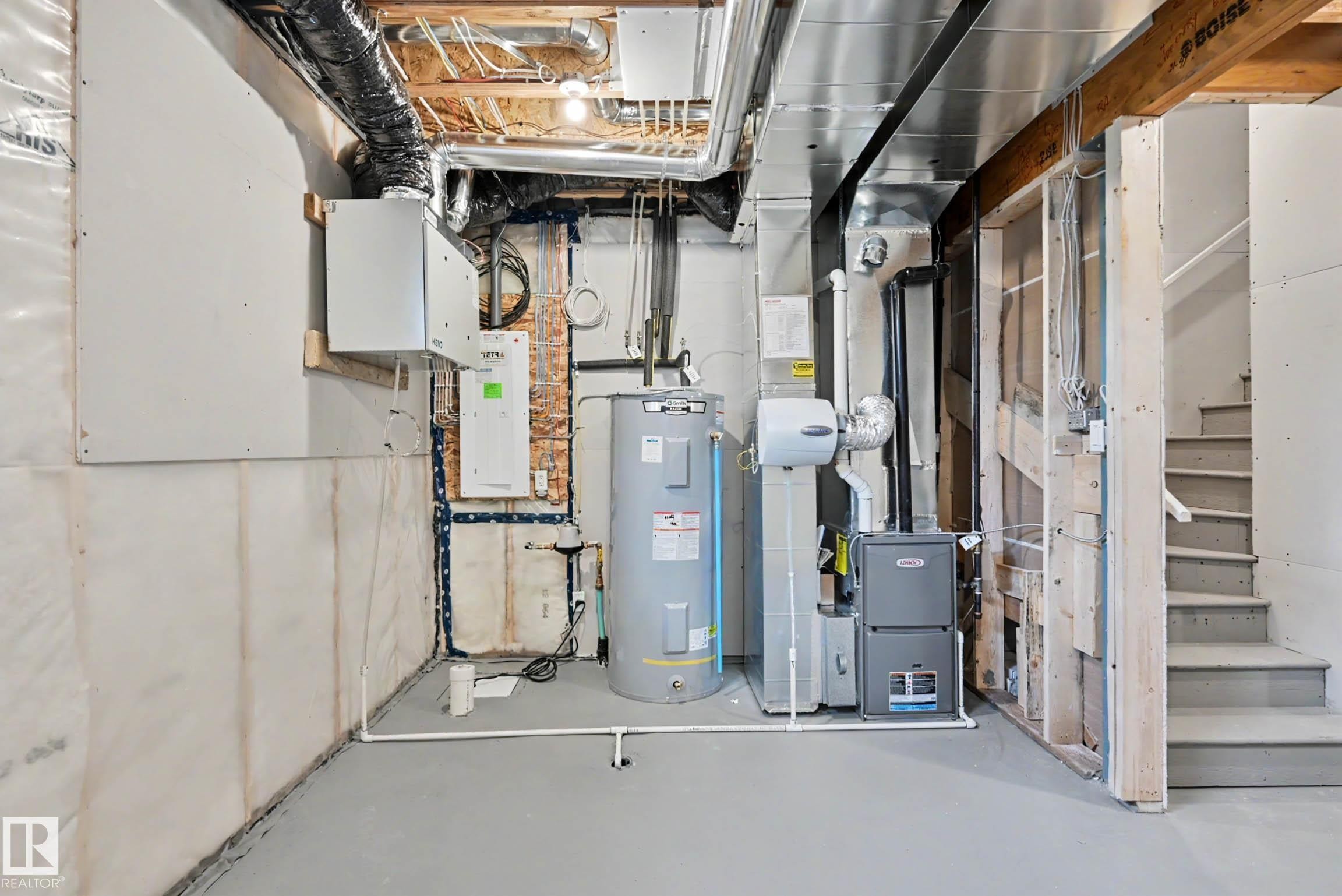 Utility room featuring a water heater, furnace, and exposed ceiling joists - 720 Southfork Drive, Leduc, AB - Indoor Photo Showing Basement