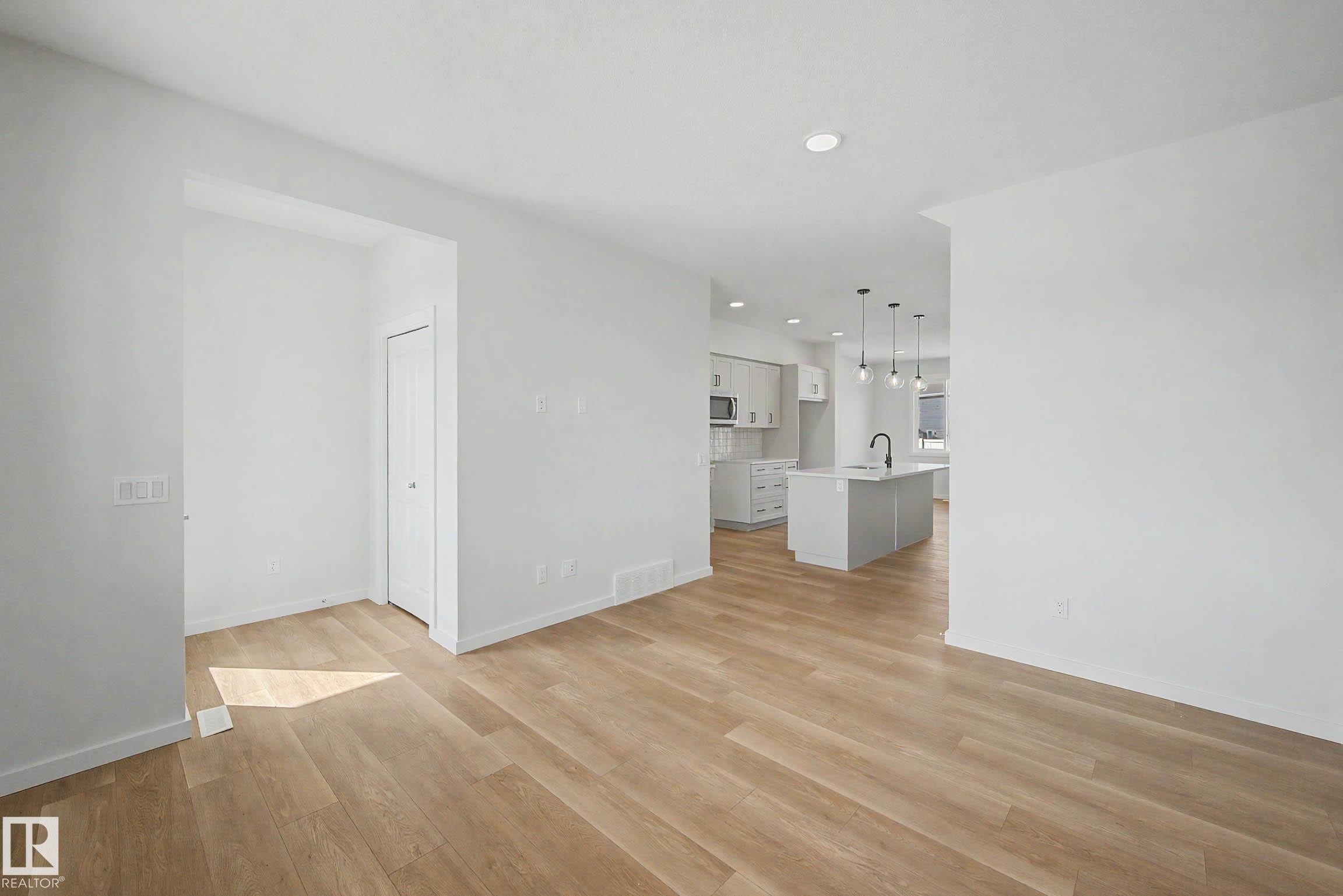 Open-concept living space featuring wood-finish flooring, recessed lighting, and white baseboards - 720 Southfork Drive, Leduc, AB - Indoor Photo Showing Other Room