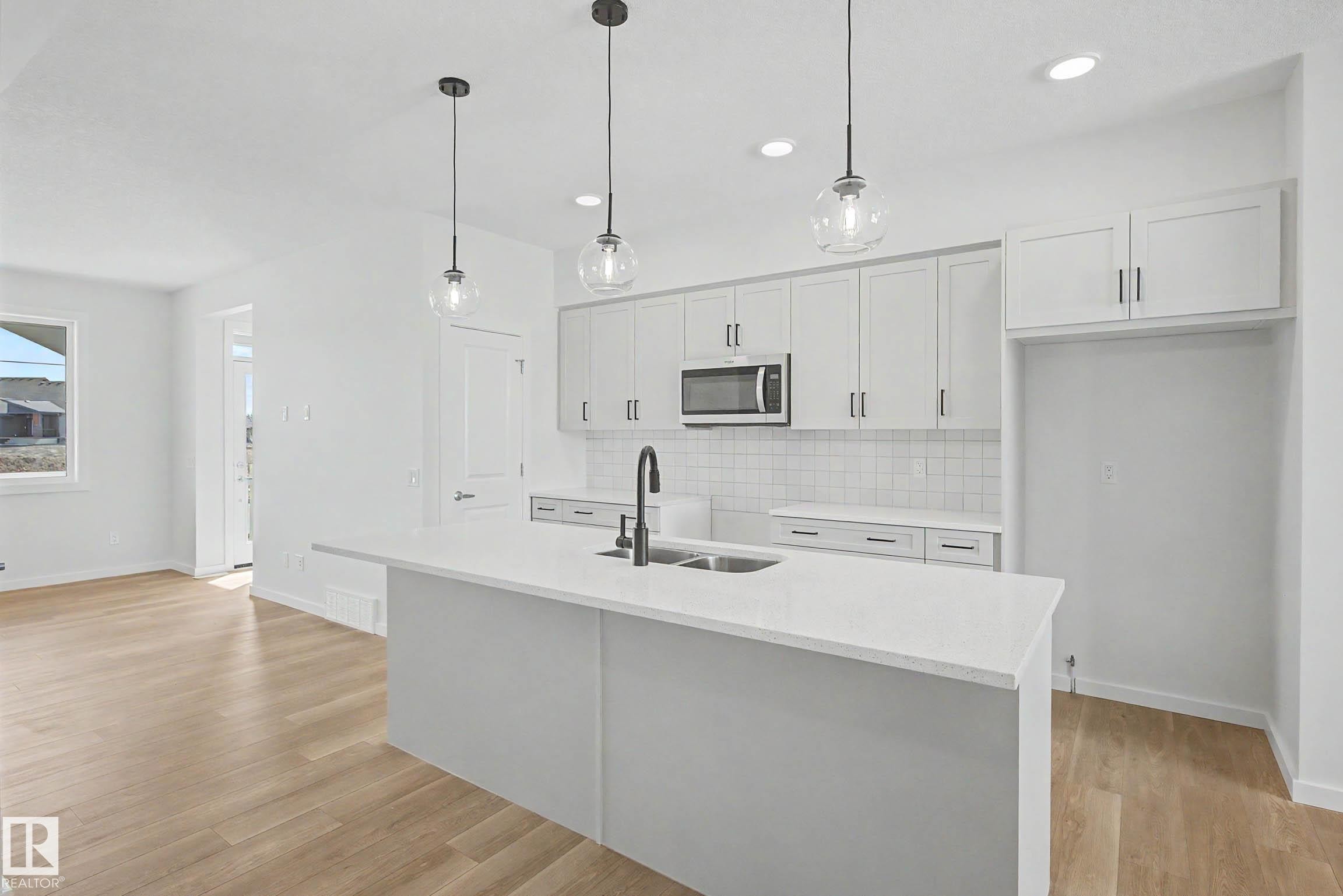 Modern kitchen featuring white shaker cabinetry, stainless steel microwave, and white subway tile backsplash - 720 Southfork Drive, Leduc, AB - Indoor Photo Showing Kitchen With Double Sink With Upgraded Kitchen