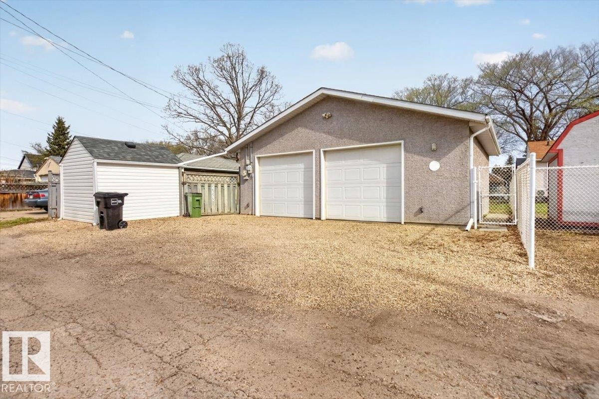 Two-car stucco garage with white panel doors and a gravel parking area - 9723 65 Avenue, Edmonton, AB - Outdoor With Exterior