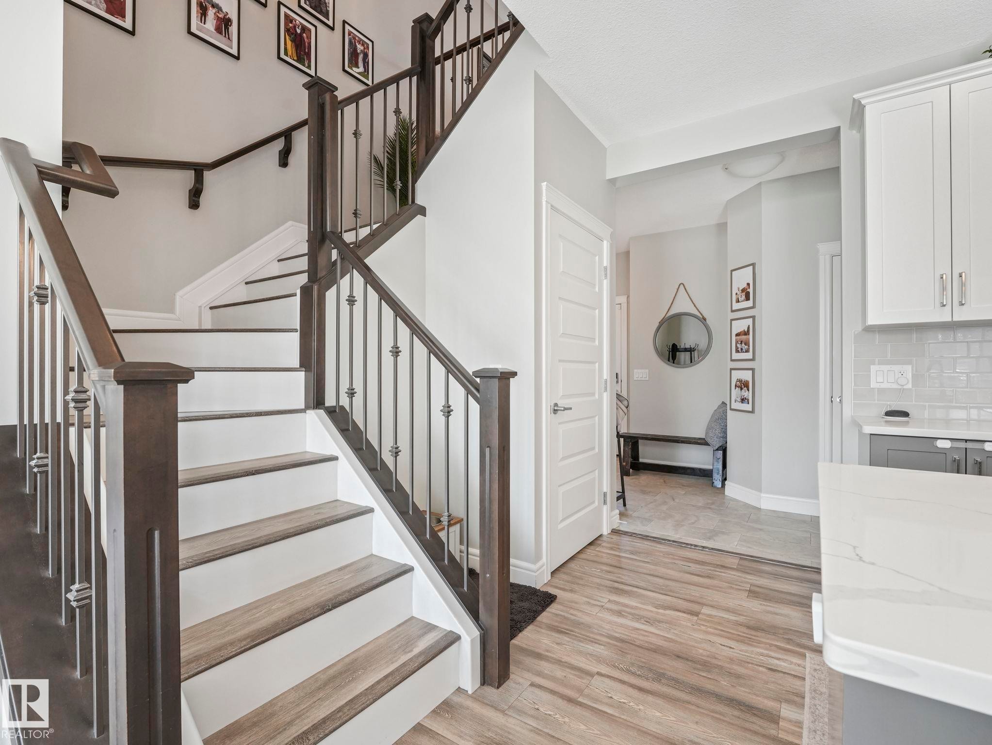 Staircase featuring wood-finish treads, white risers, and dark wood newel posts with iron balusters - 3817 Robins Crescent, Edmonton, AB - Indoor Photo Showing Other Room