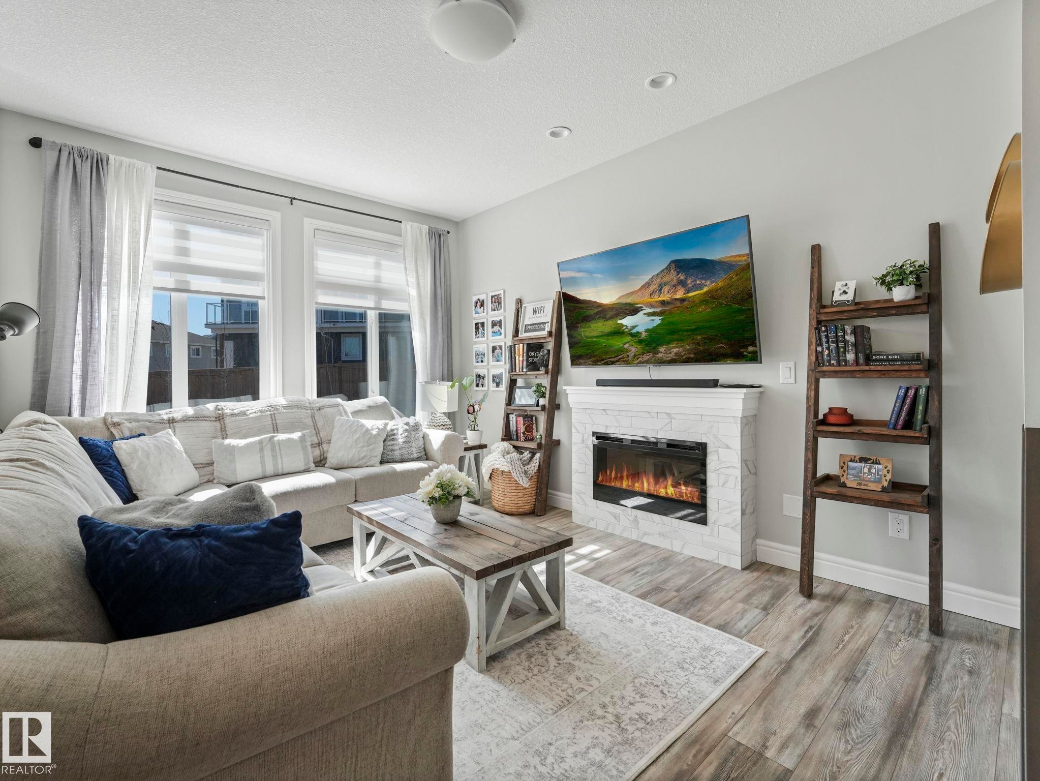 Living area featuring wide plank wood-finish flooring - 3817 Robins Crescent, Edmonton, AB - Indoor Photo Showing Living Room With Fireplace