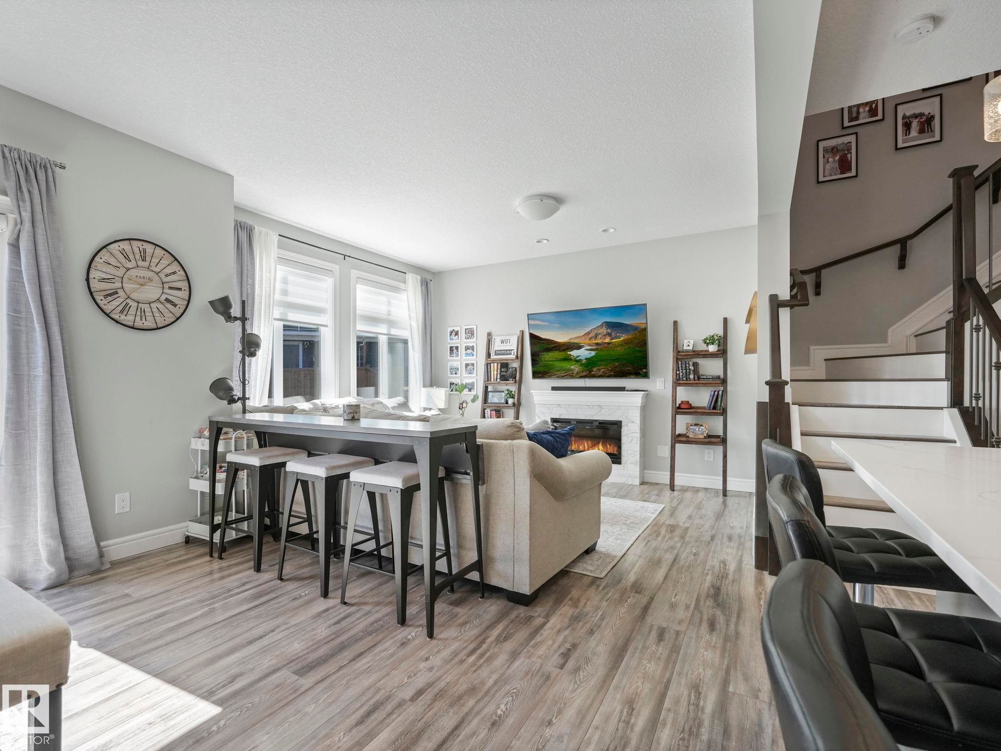 Living area featuring wood-finish flooring, a white fireplace with a mantel, and multiple windows with blinds - 3817 Robins Crescent, Edmonton, AB - Indoor With Fireplace