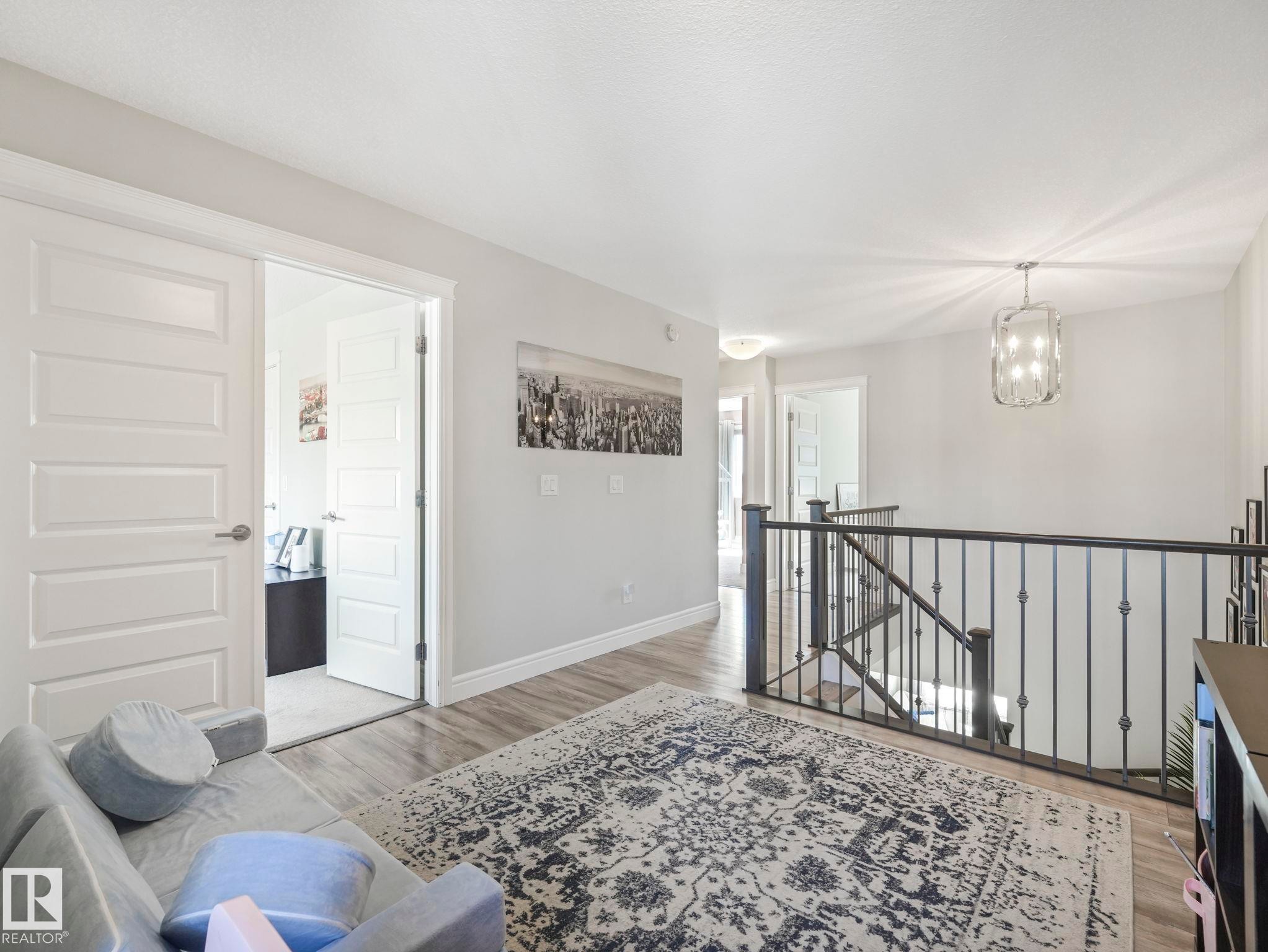 Hallway with wood-finish flooring, white trim, and light gray walls - 3817 Robins Crescent, Edmonton, AB - Indoor Photo Showing Other Room
