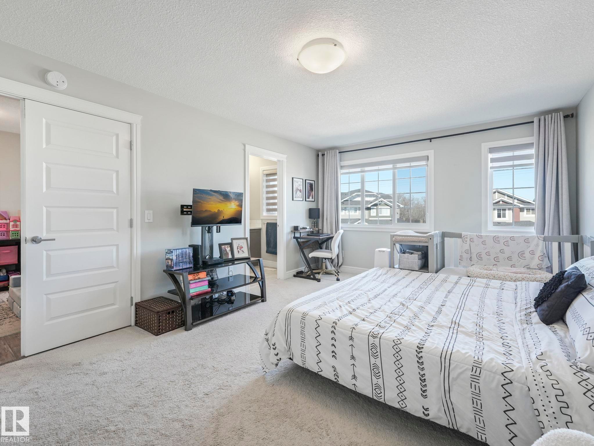 Carpeted room featuring multiple windows with roller shades, a ceiling-mounted light fixture, and a five-panel interior door - 3817 Robins Crescent, Edmonton, AB - Indoor Photo Showing Bedroom