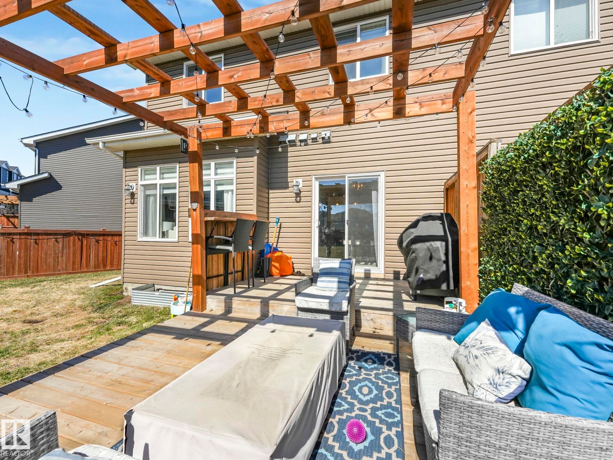 Expansive outdoor living area featuring a multi-level wood deck, a prominent wood pergola with integrated string lights, and a sliding glass door for interior access - 3817 Robins Crescent, Edmonton, AB - Outdoor
