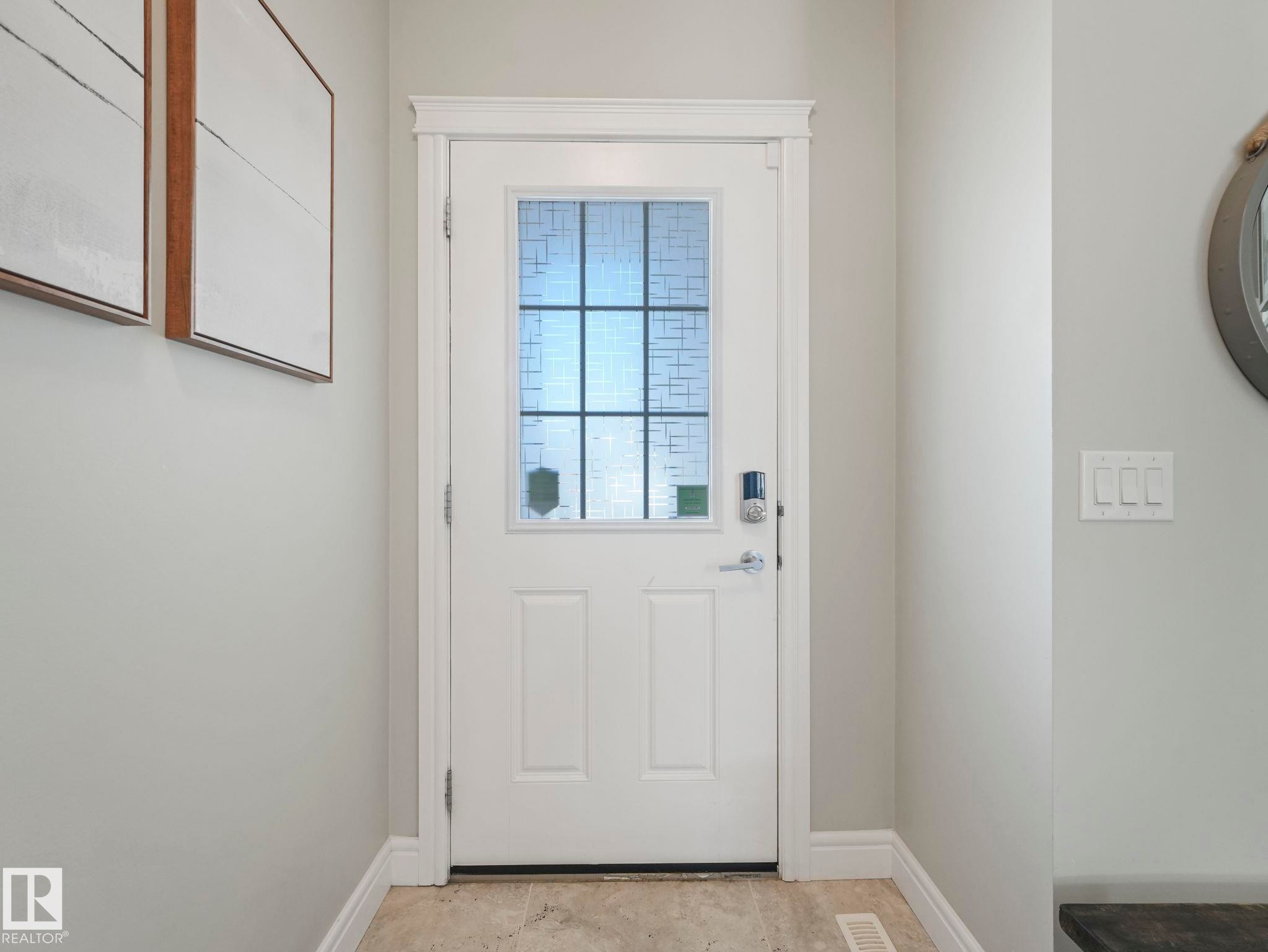 White entry door featuring a multi-pane window with privacy glass, a smart lock, and brushed nickel hardware - 3817 Robins Crescent, Edmonton, AB - Indoor Photo Showing Other Room