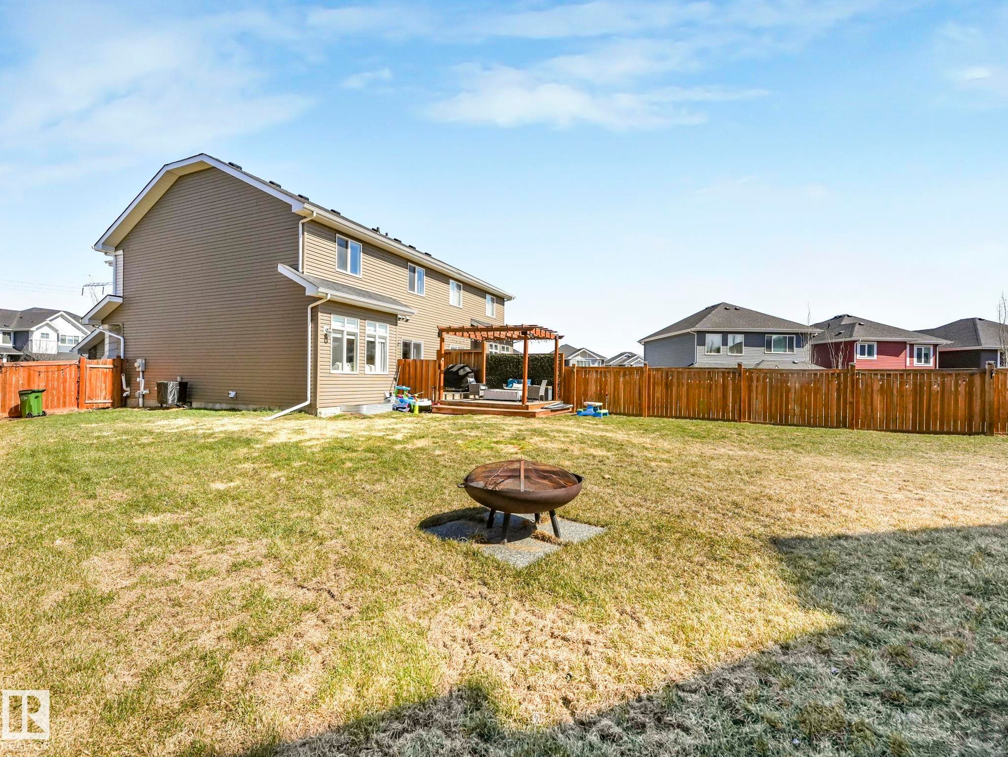 Spacious backyard featuring a wooden privacy fence, a multi-level deck with a pergola, and a visible fire pit - 3817 Robins Crescent, Edmonton, AB - Outdoor