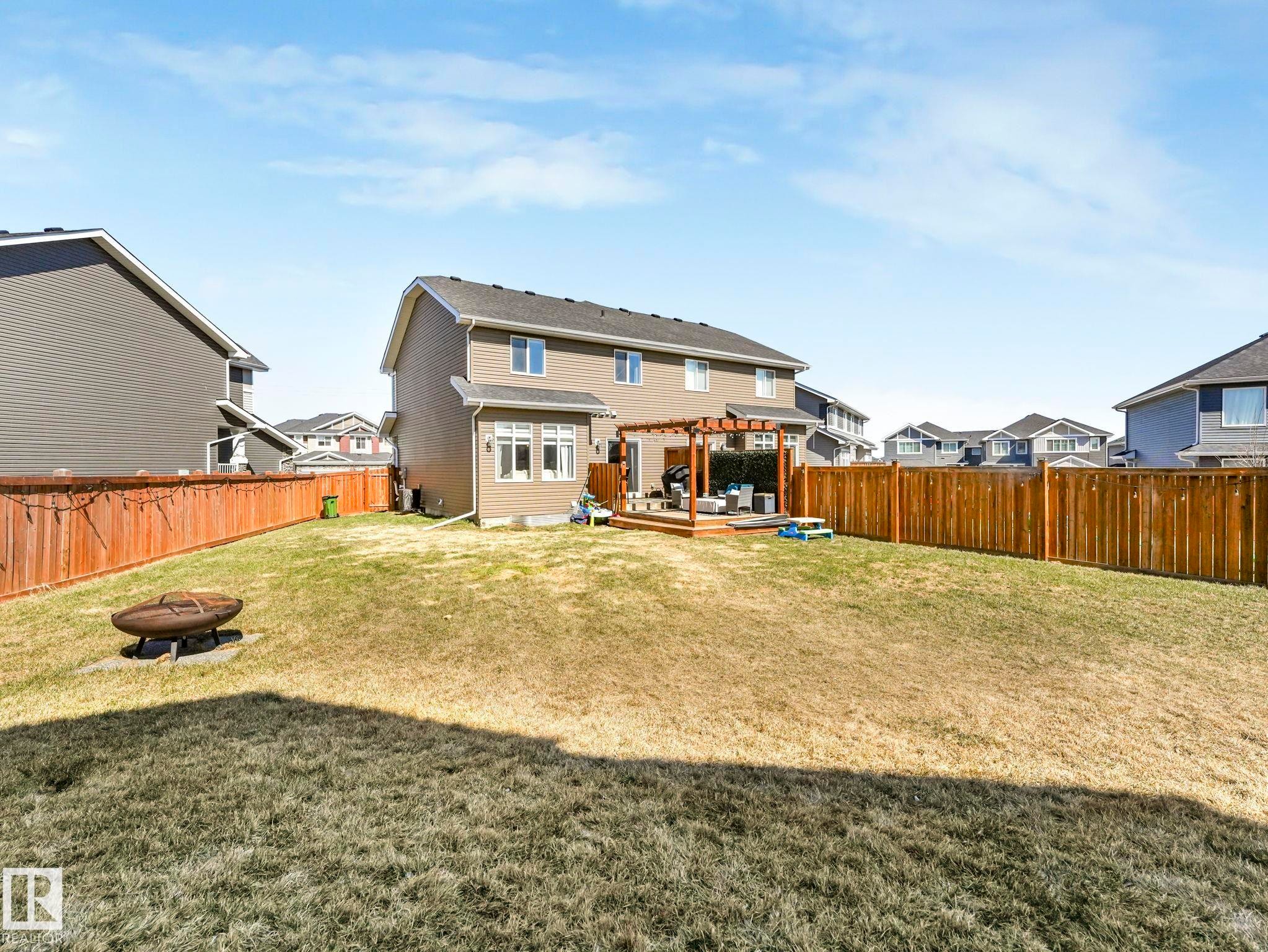 Expansive backyard featuring a large wooden deck with pergola, privacy fencing, and a built-in fire pit - 3817 Robins Crescent, Edmonton, AB - Outdoor