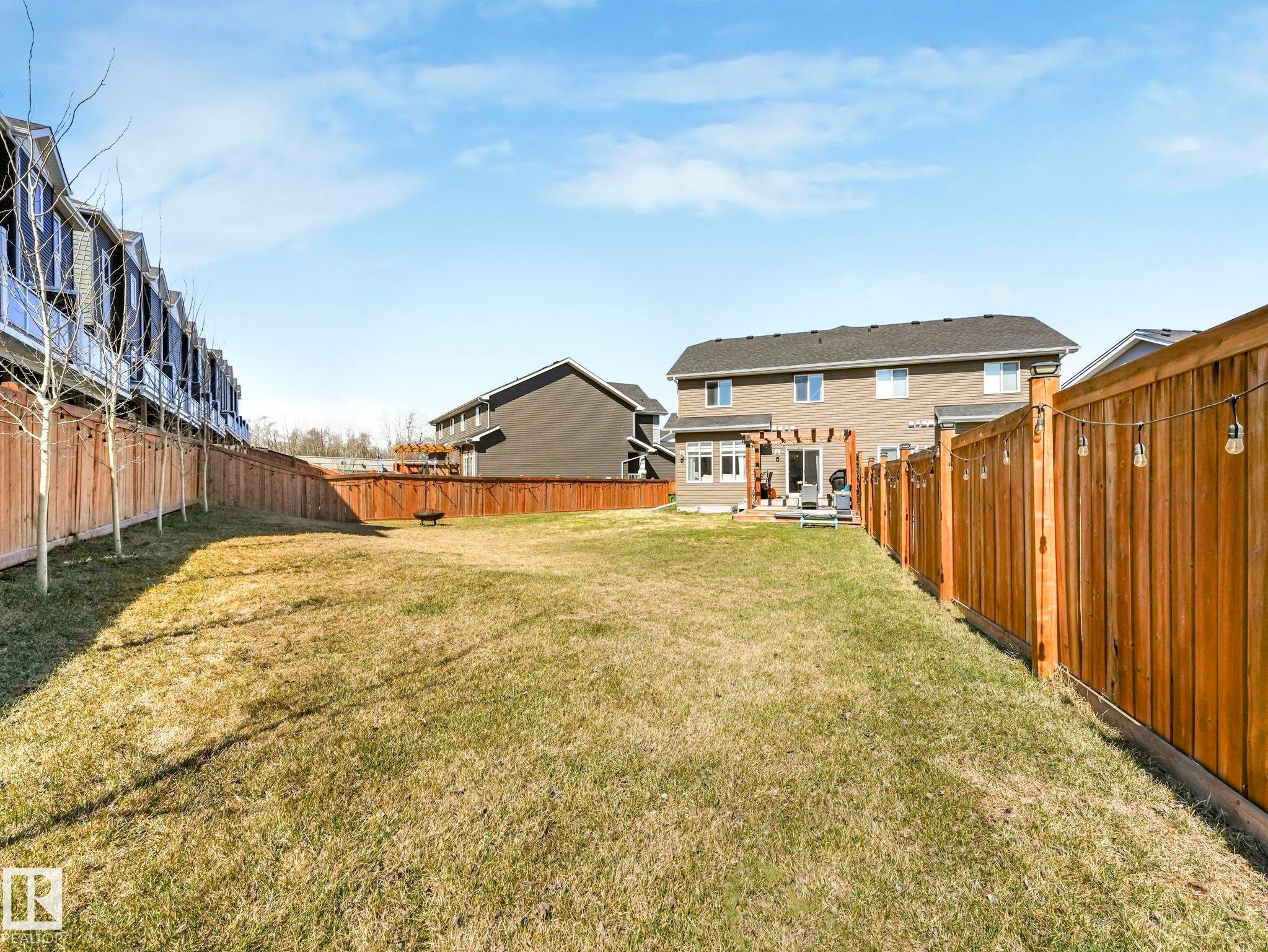 Expansive backyard featuring a spacious lawn, wood privacy fencing, and a rear deck with a pergola - 3817 Robins Crescent, Edmonton, AB - Outdoor