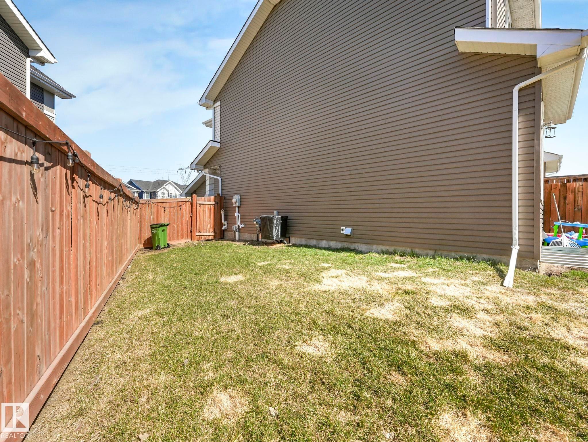 Expansive lawn area enclosed by a wood privacy fence with a gated entry - 3817 Robins Crescent, Edmonton, AB - Outdoor With Exterior