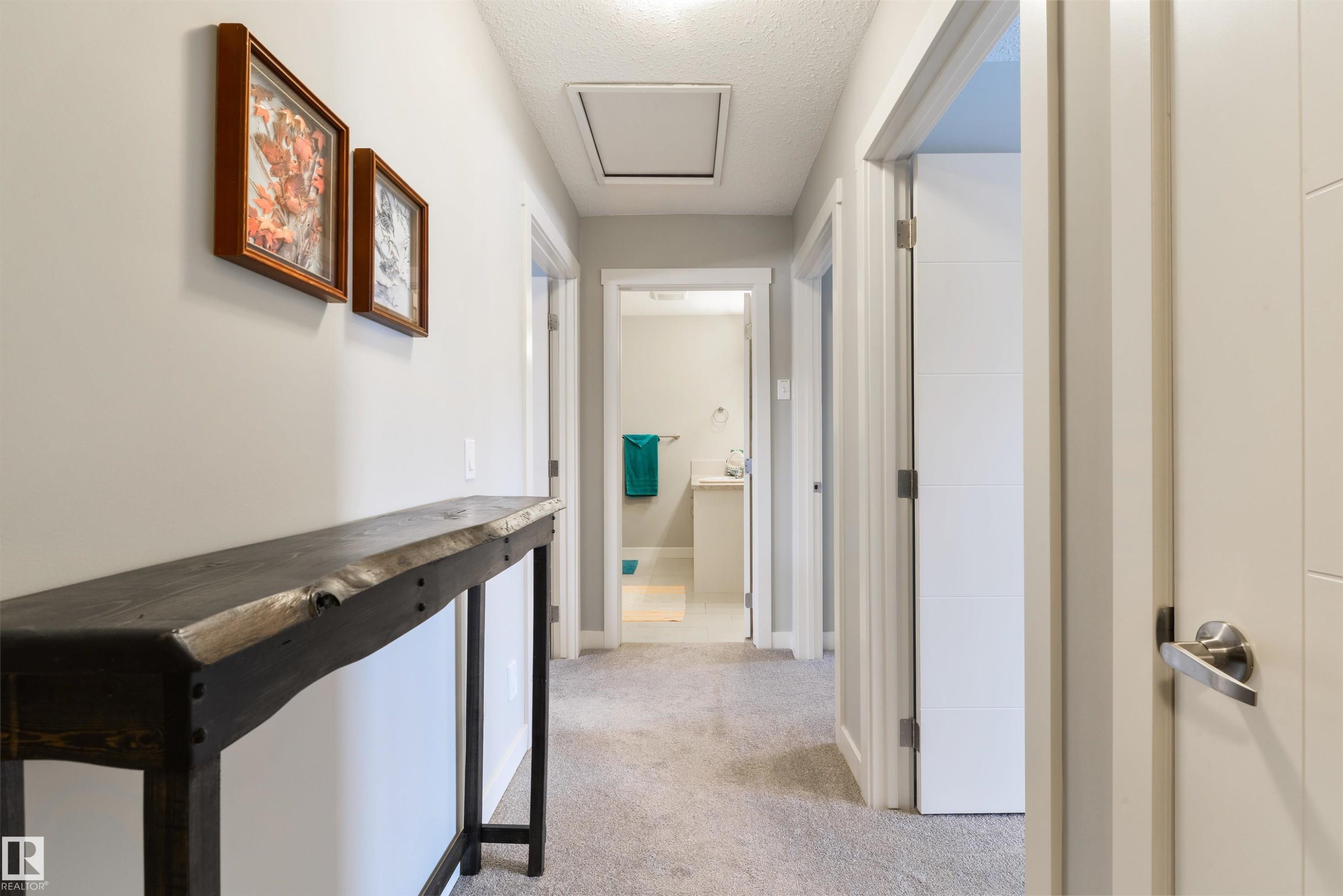 Hallway featuring light gray carpeting, crisp white trim, and multiple interior doors with modern hardware - 4914 47 Street, Redwater, AB - Indoor Photo Showing Other Room