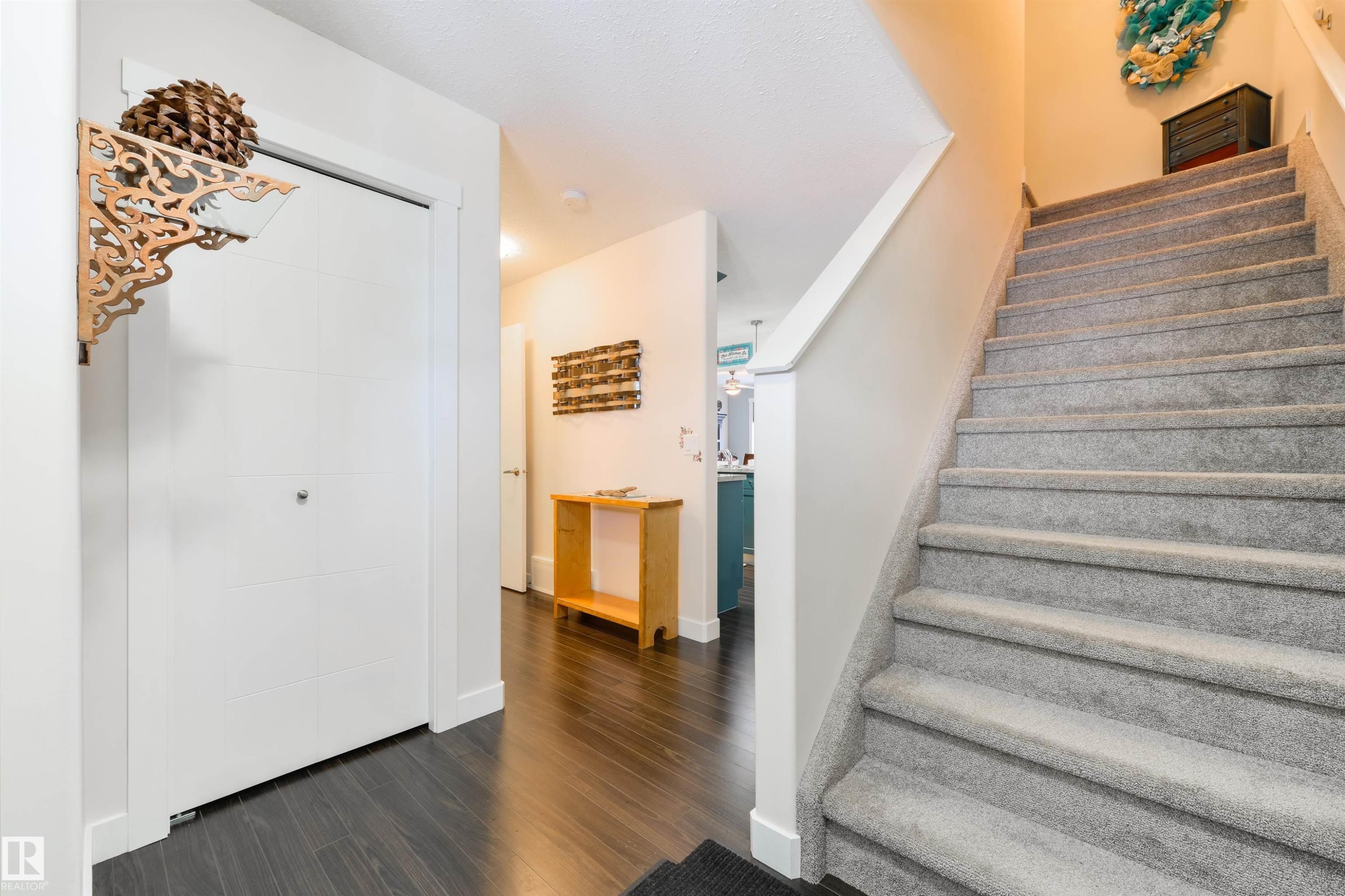 Carpeted staircase with white balustrade, dark wood-finish flooring, and white baseboards - 4914 47 Street, Redwater, AB - Indoor Photo Showing Other Room