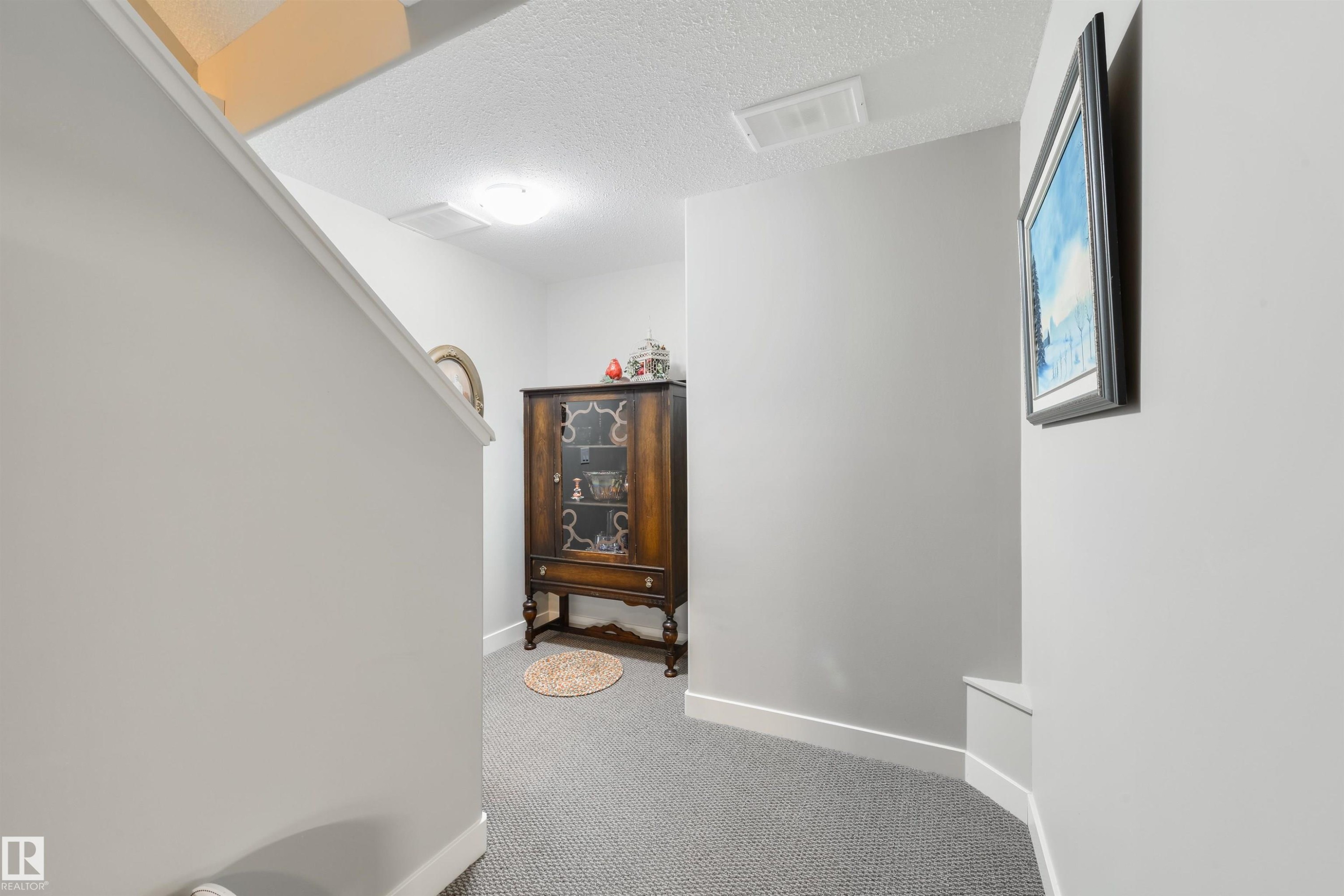 Carpeted hallway with light gray walls, white trim, and a white ceiling - 4914 47 Street, Redwater, AB - Indoor Photo Showing Other Room