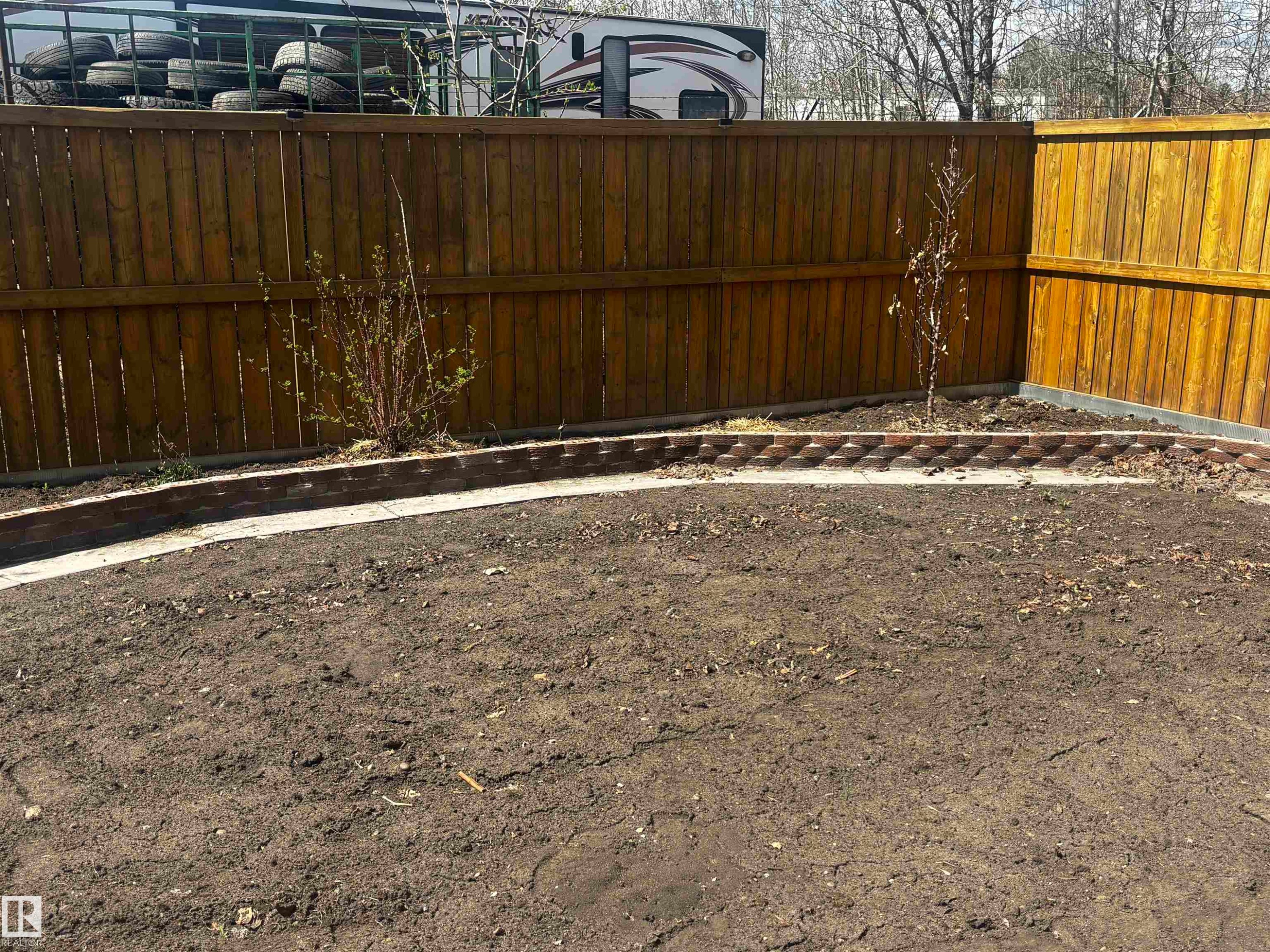 Expansive backyard with a new wood fence perimeter and curved stone paver garden edging - 4914 47 Street, Redwater, AB - Outdoor