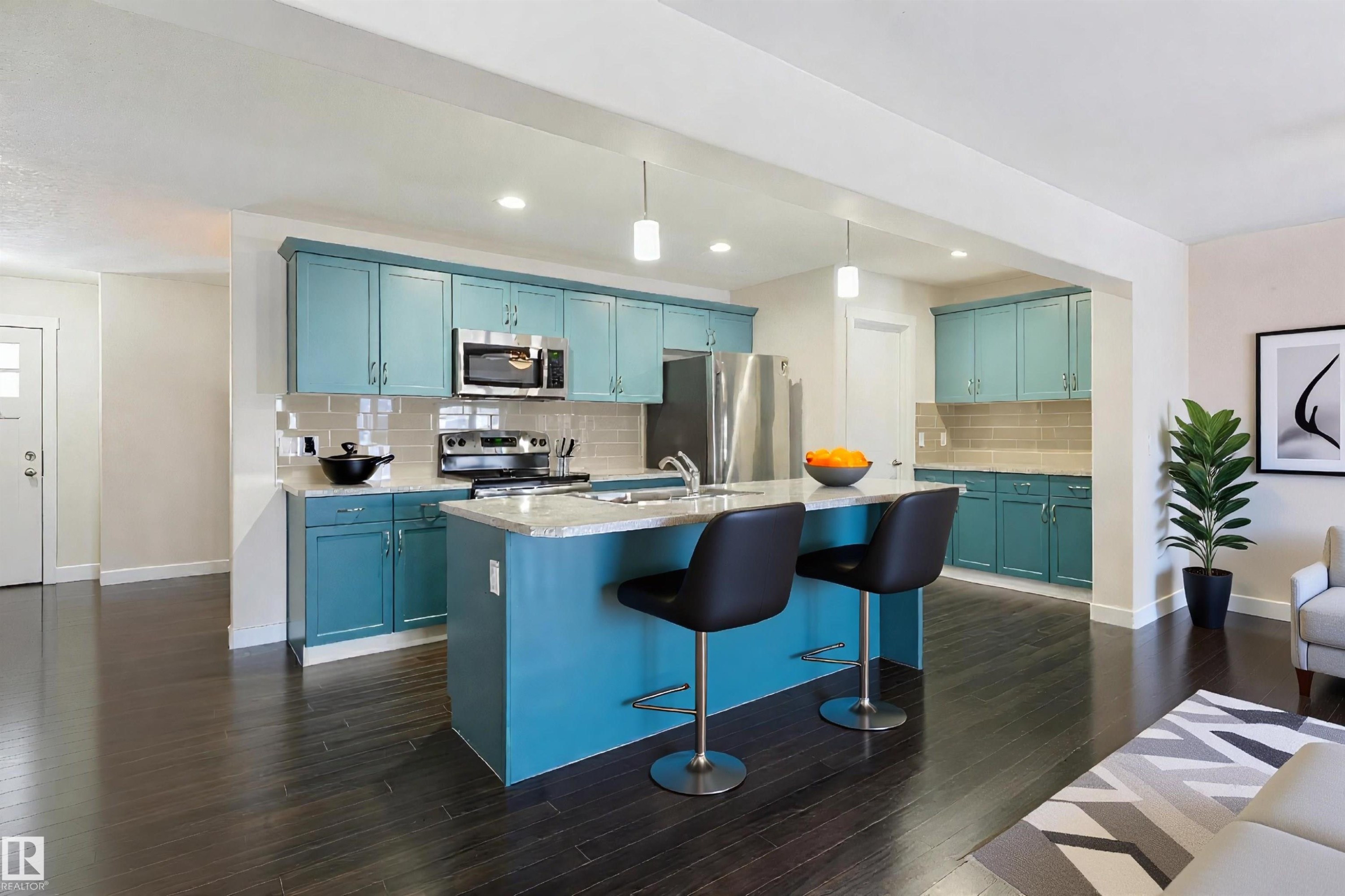 Kitchen featuring a central island with a light-toned countertop, teal cabinetry, stainless steel appliances, dark wood-finish flooring, and recessed lighting - 4914 47 Street, Redwater, AB - Indoor Photo Showing Kitchen With Upgraded Kitchen
