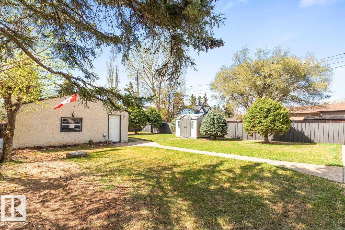 Expansive rear yard featuring a manicured lawn, established trees, and a utility shed - 10502 158 Street, Edmonton, AB - Outdoor