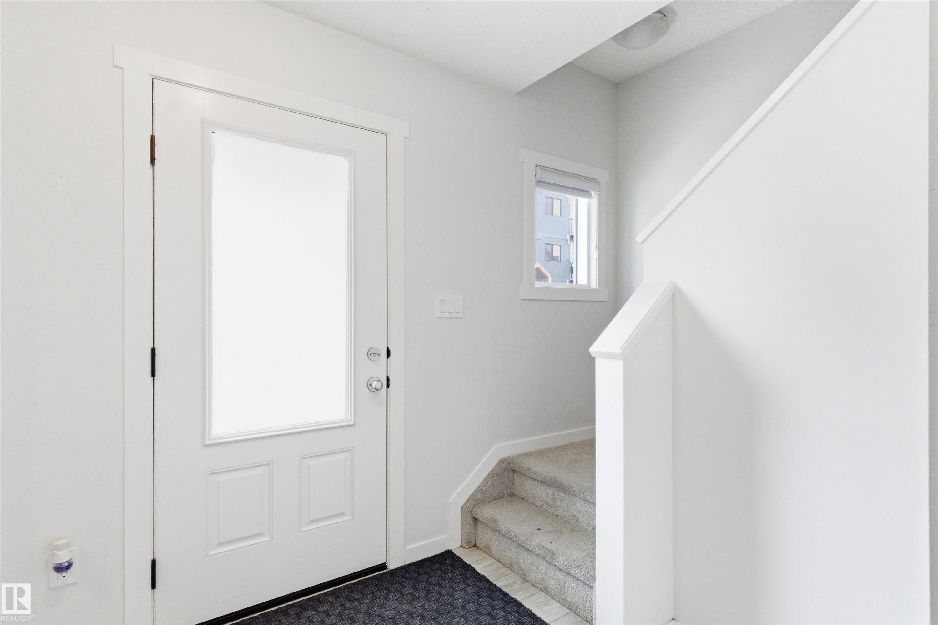 Entryway featuring a white door with frosted glass panel, contrasting dark hardware, and white trim - 9 850 Secord Boulevard, Edmonton, AB - Indoor Photo Showing Other Room
