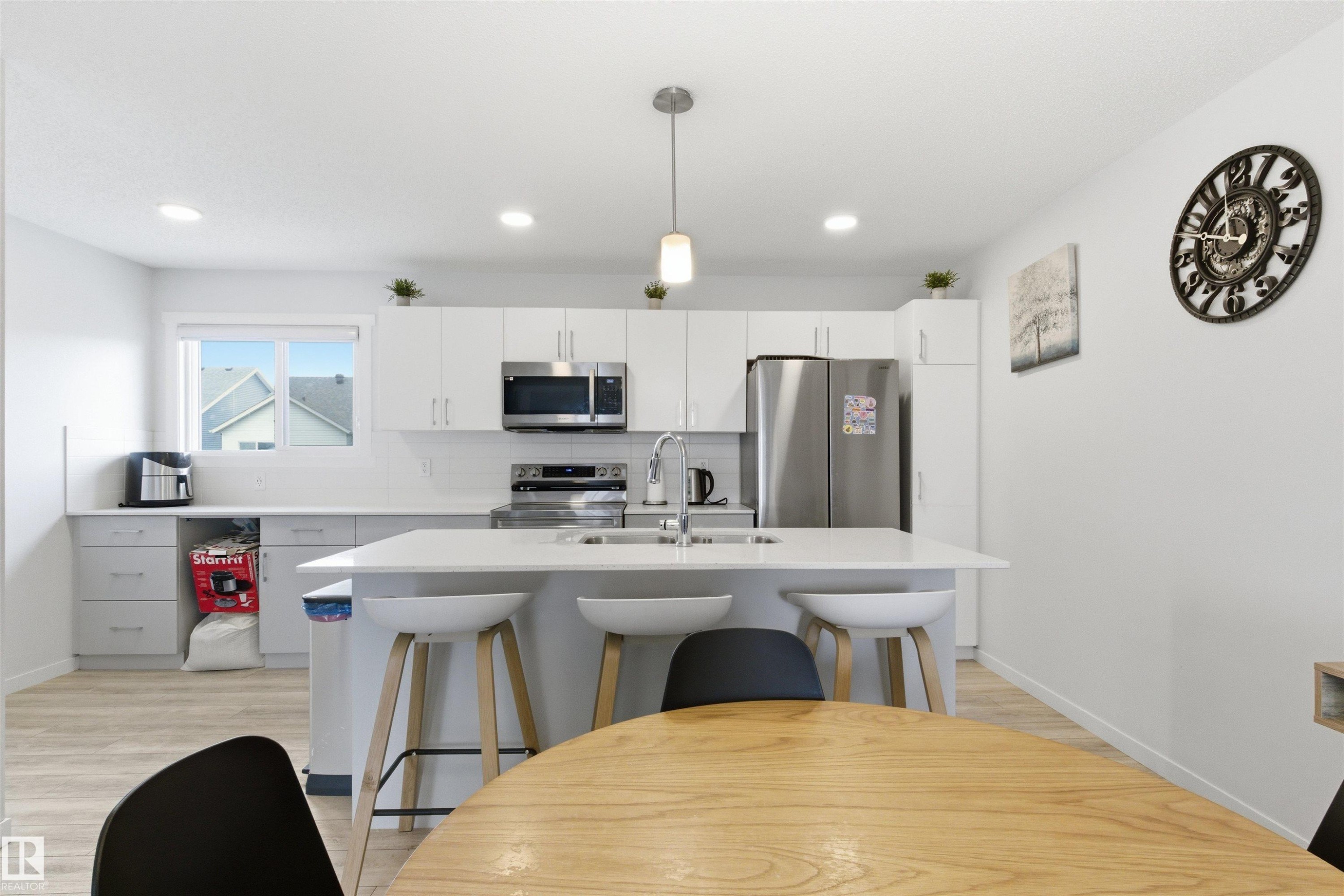Modern kitchen featuring white cabinetry, stainless steel appliances, a center island with bar seating, a tile backsplash, and recessed lighting - 9 850 Secord Boulevard, Edmonton, AB - Indoor