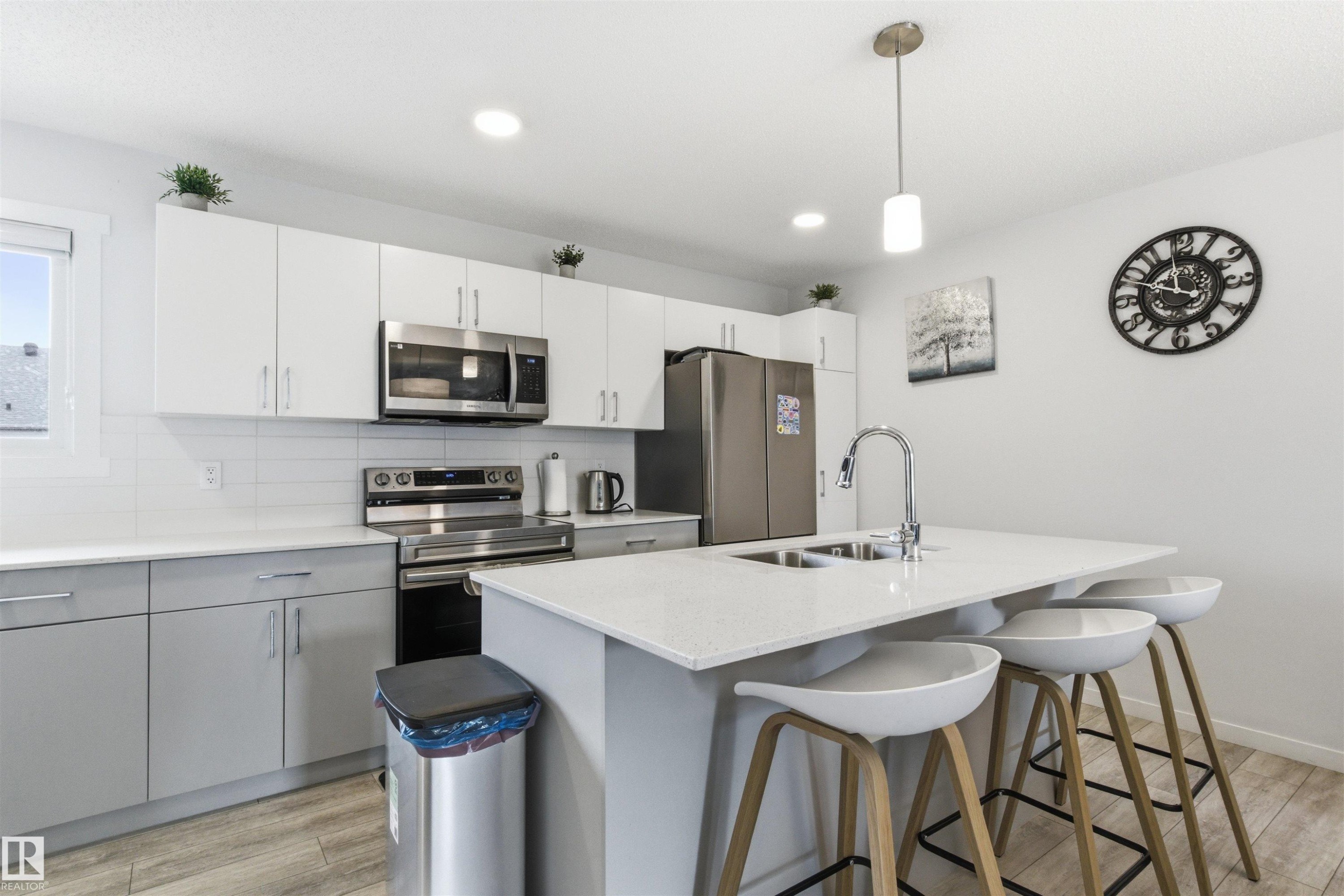 Modern kitchen featuring a central island with integrated double-basin sink and bar seating - 9 850 Secord Boulevard, Edmonton, AB - Indoor Photo Showing Kitchen With Double Sink With Upgraded Kitchen