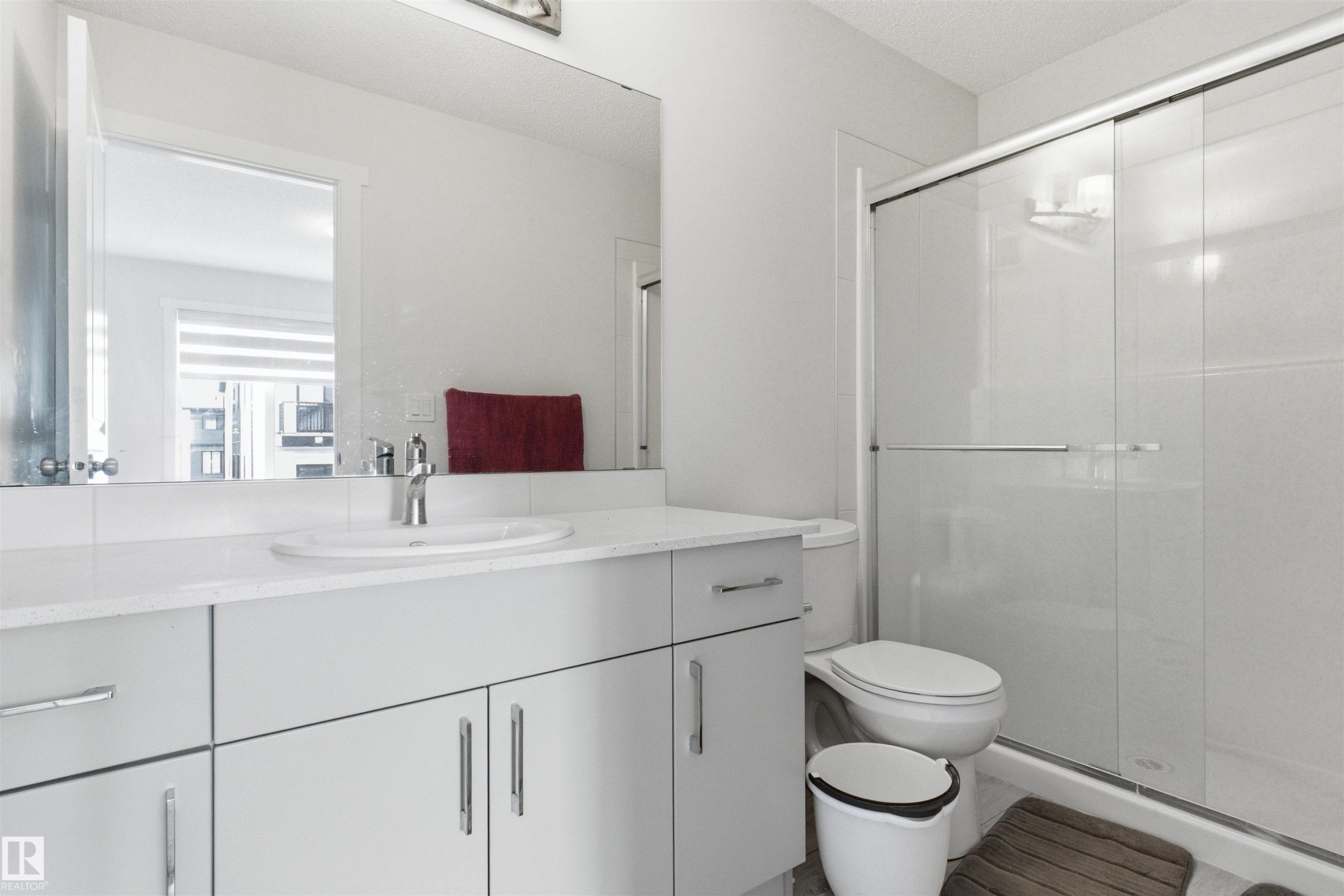 Bathroom featuring a white vanity with an integrated sink, polished chrome faucet, and ample storage cabinetry - 9 850 Secord Boulevard, Edmonton, AB - Indoor Photo Showing Bathroom