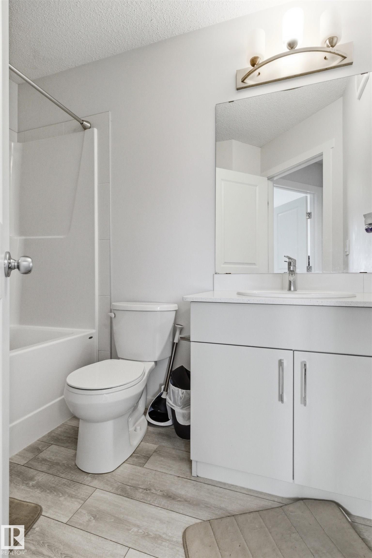 Bright bathroom featuring a white vanity with contemporary hardware, an integrated sink, and a framed mirror - 9 850 Secord Boulevard, Edmonton, AB - Indoor Photo Showing Bathroom