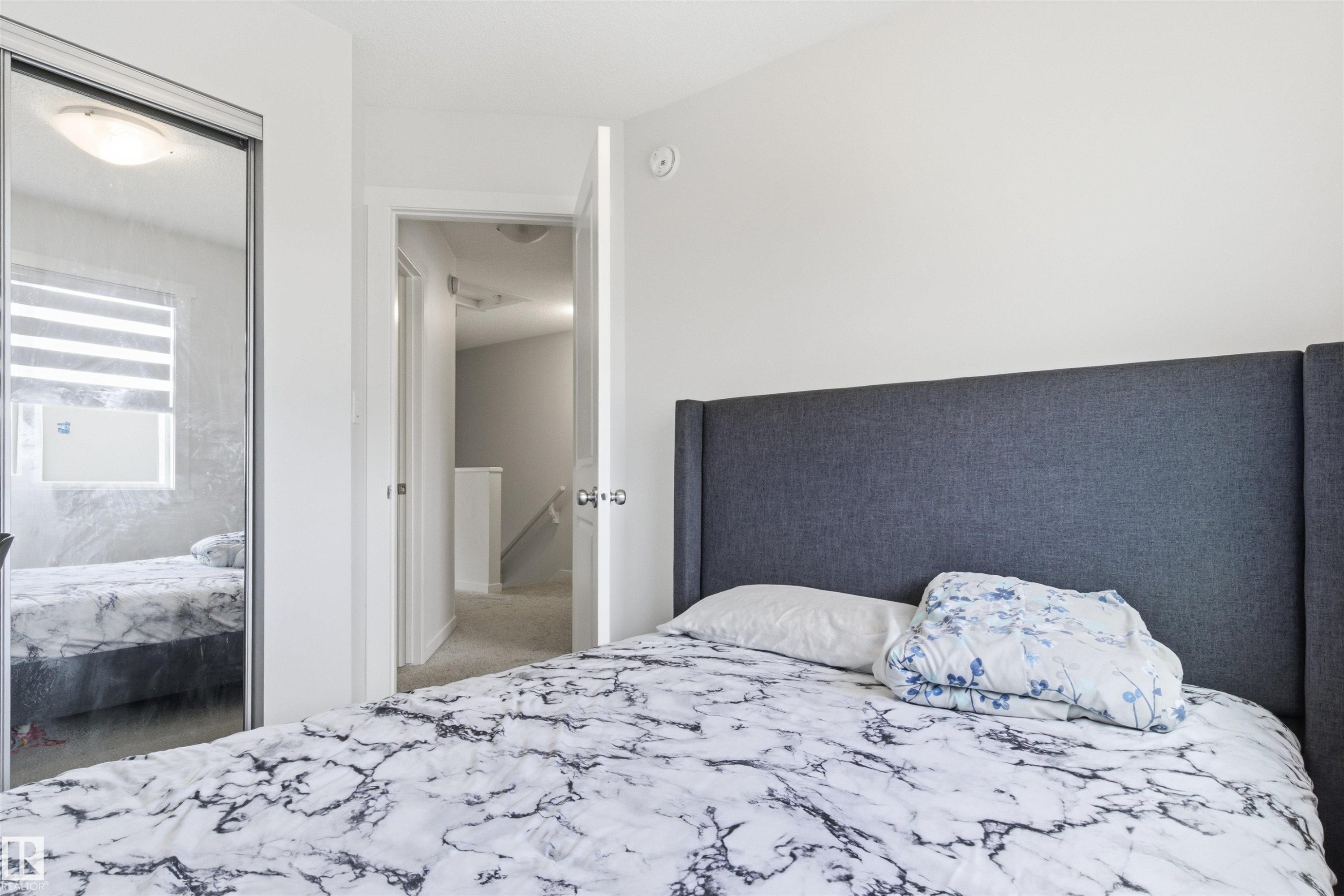 Room featuring a mirrored closet door, a flush-mount ceiling light fixture, and white wall finishes - 9 850 Secord Boulevard, Edmonton, AB - Indoor Photo Showing Bedroom