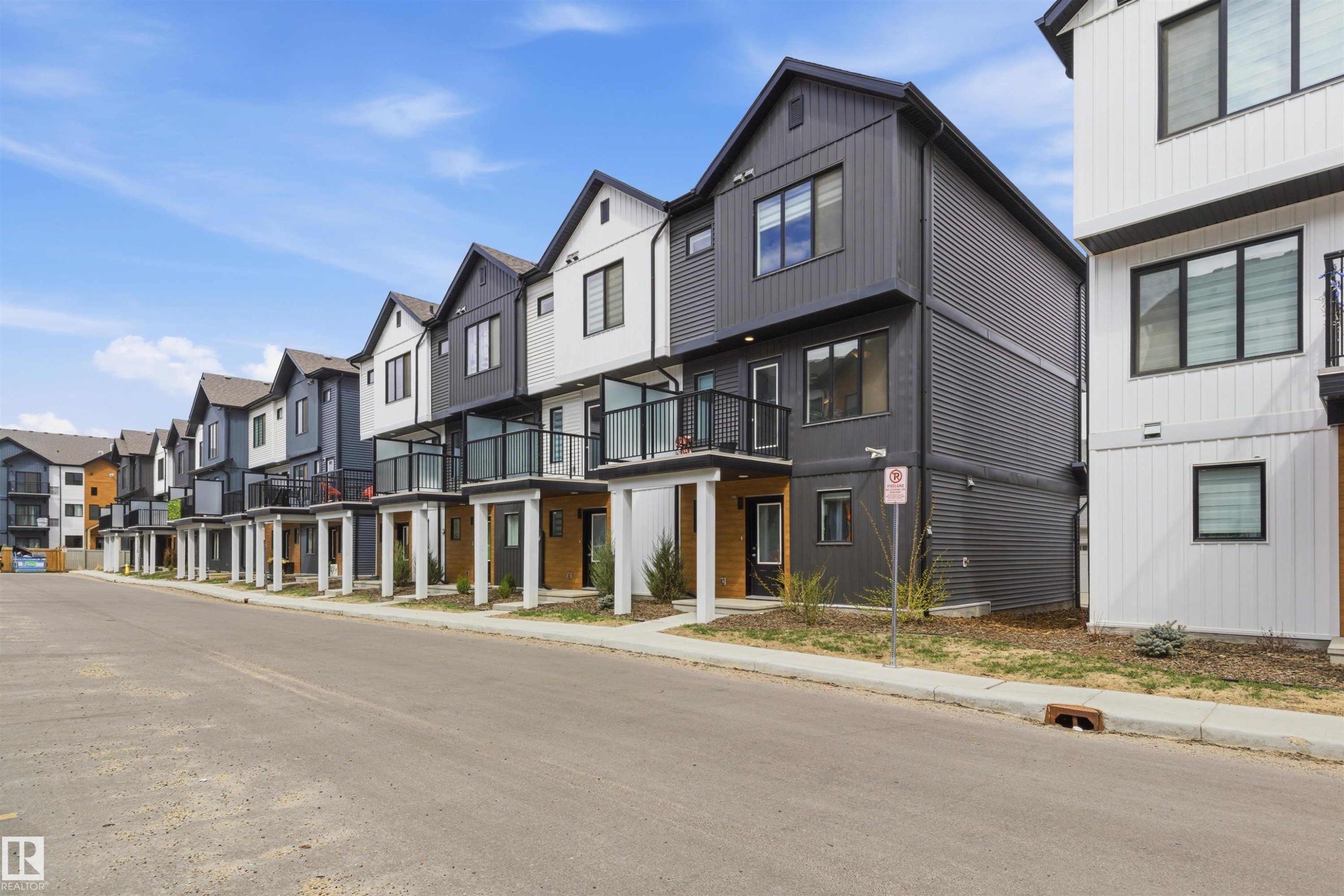 Contemporary townhomes featuring a mix of vertical and horizontal siding, private balconies with glass railings, and a consistent modern architectural aesthetic - 9 850 Secord Boulevard, Edmonton, AB - Outdoor