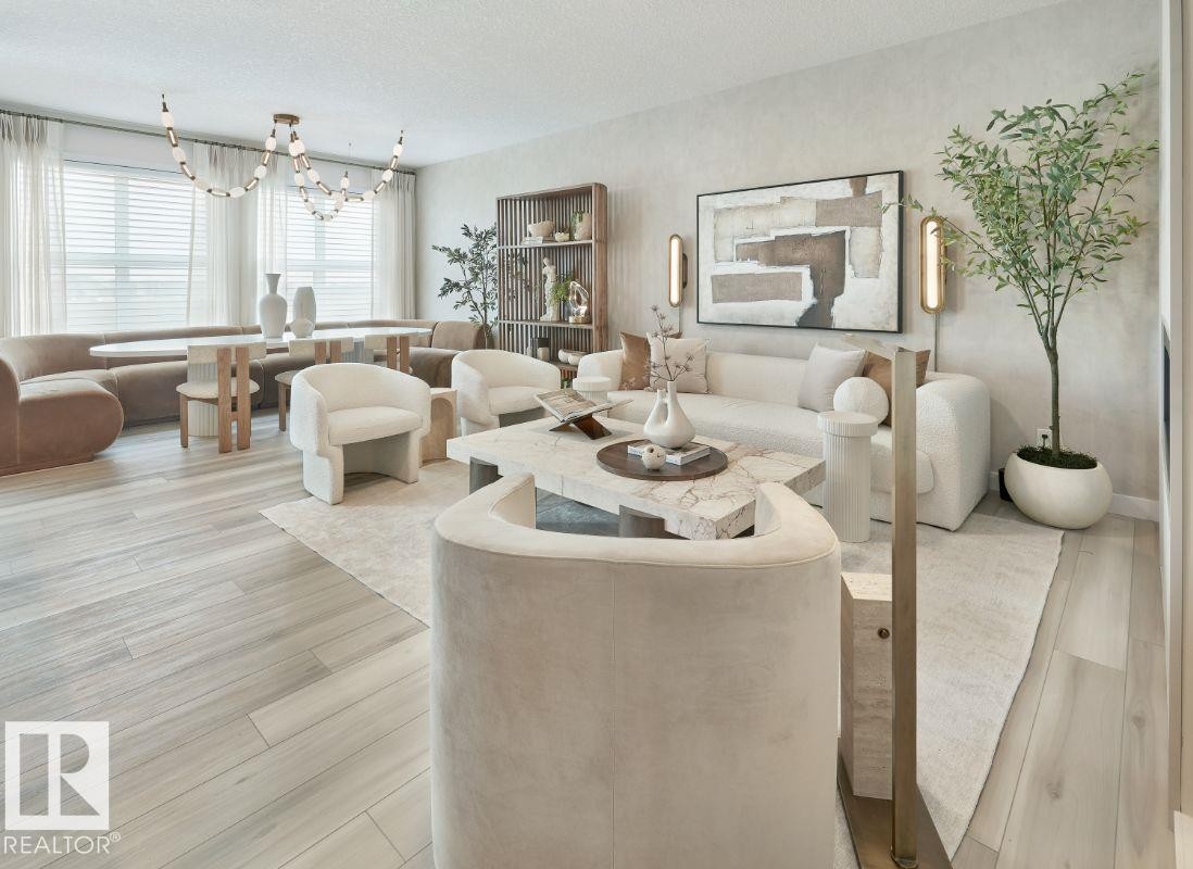 Living room featuring light wood finished floors, a chandelier, and a textured ceiling - 2131 194 Street Nw, Edmonton, AB - Indoor