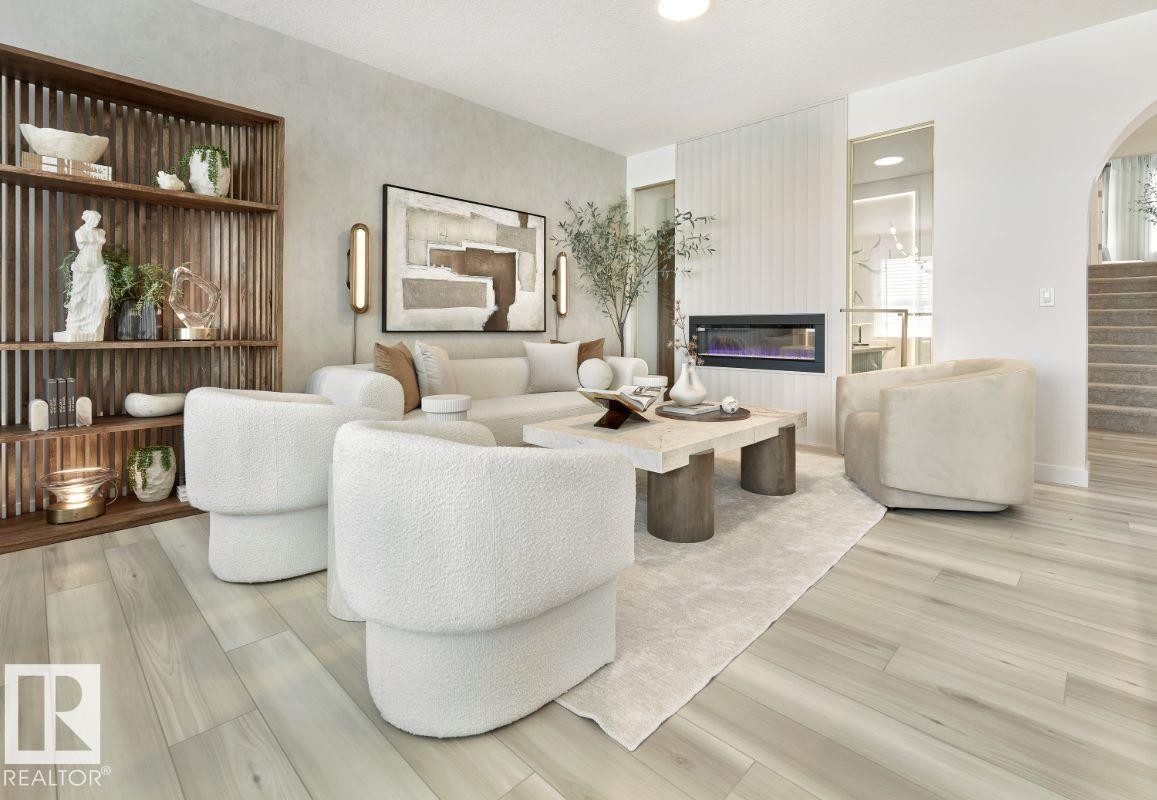 Living area featuring a glass covered fireplace, recessed lighting, light wood-style floors, and arched walkways - 2131 194 Street Nw, Edmonton, AB - Indoor Photo Showing Living Room With Fireplace