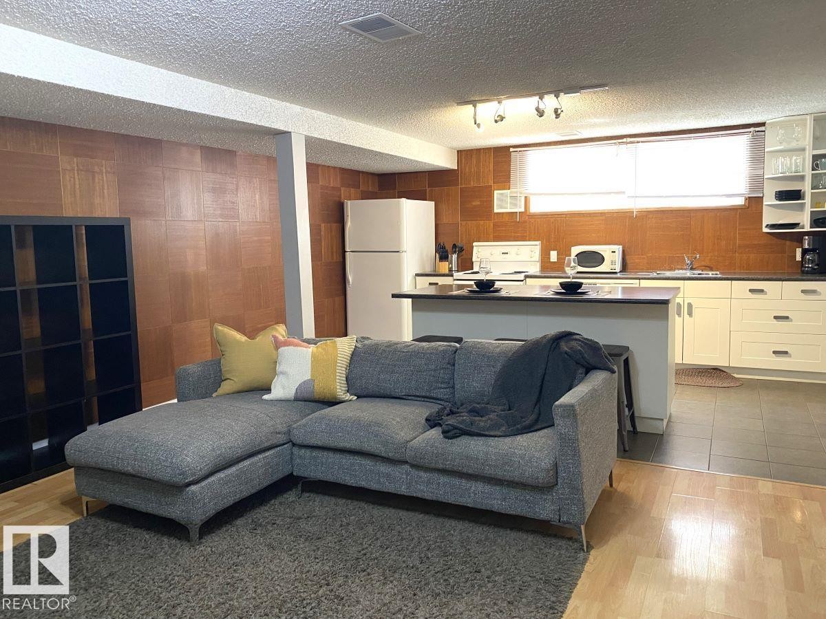 Open-concept living space featuring wood-finish wall paneling and recessed ceiling beams - 8239 93A Avenue, Edmonton, AB - Indoor
