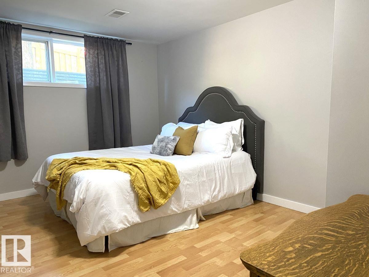 Bedroom featuring light wood-finish flooring, neutral wall tones, and a window with white trim - 8239 93A Avenue, Edmonton, AB - Indoor Photo Showing Bedroom