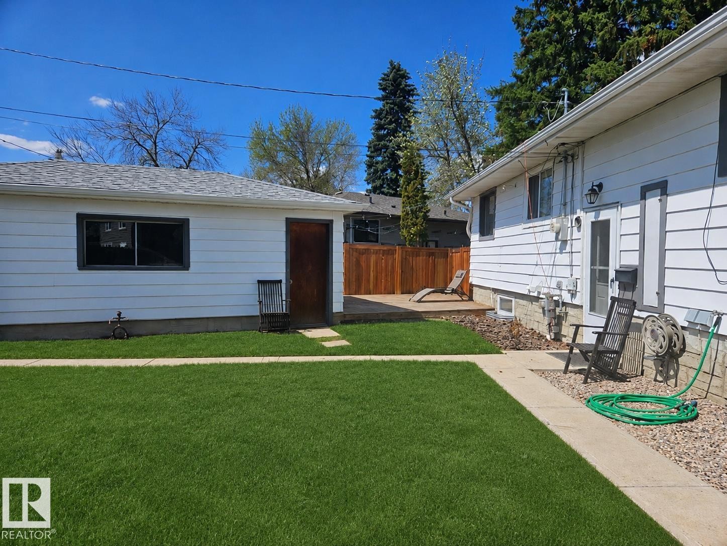 Expansive green lawn with a concrete pathway leading to a wood deck - 8239 93A Avenue, Edmonton, AB - Outdoor