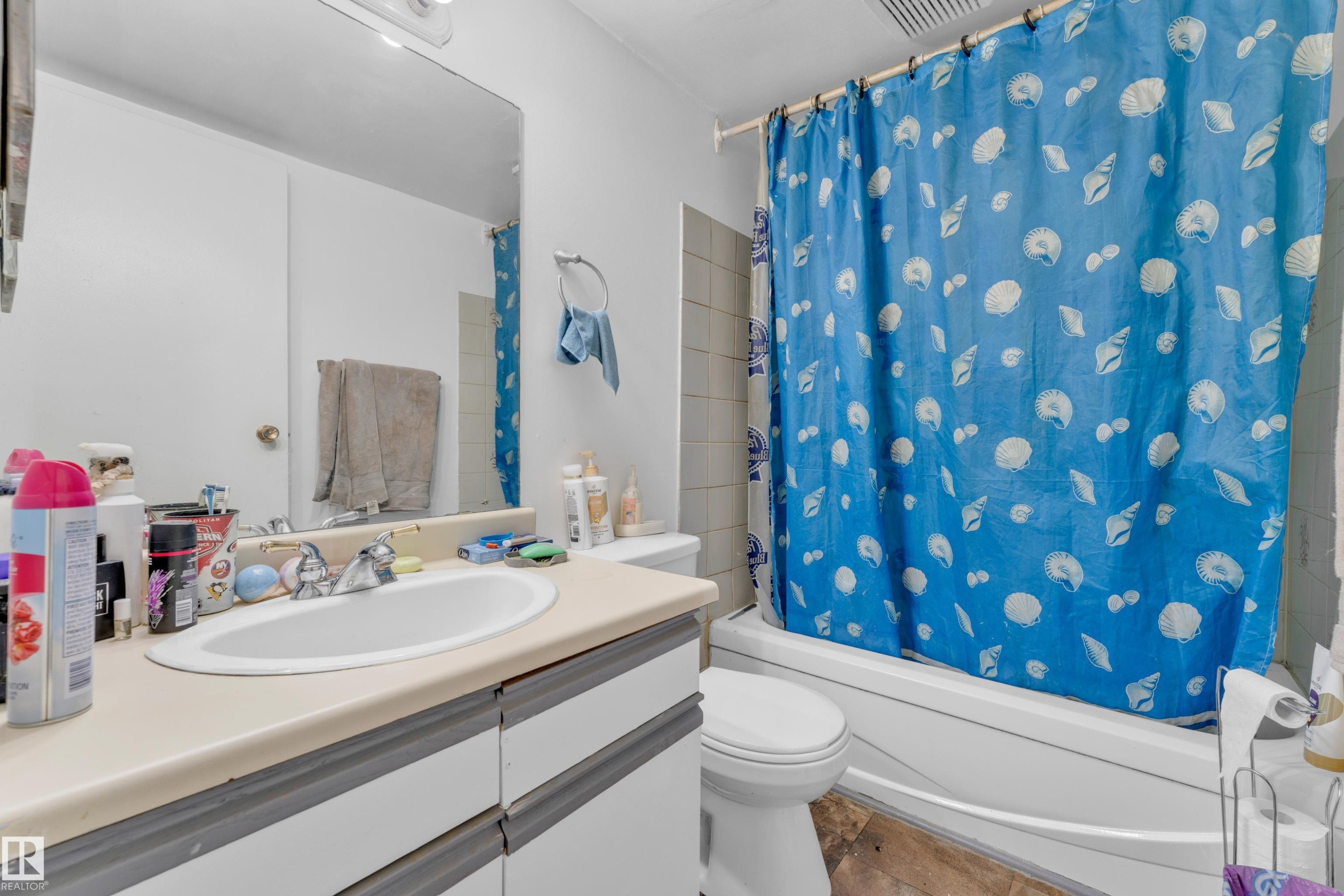 Bathroom featuring a white integrated sink, light-toned countertop, and a built-in vanity with cabinetry - 101 10136 160 Street Nw, Edmonton, AB - Indoor Photo Showing Bathroom