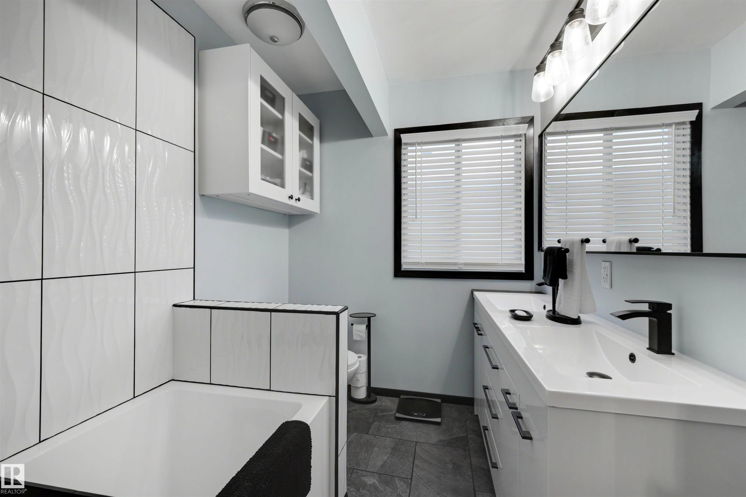 Modern bathroom featuring a built-in tub with textured white wall tiling - 9602 85 Street, Edmonton, AB