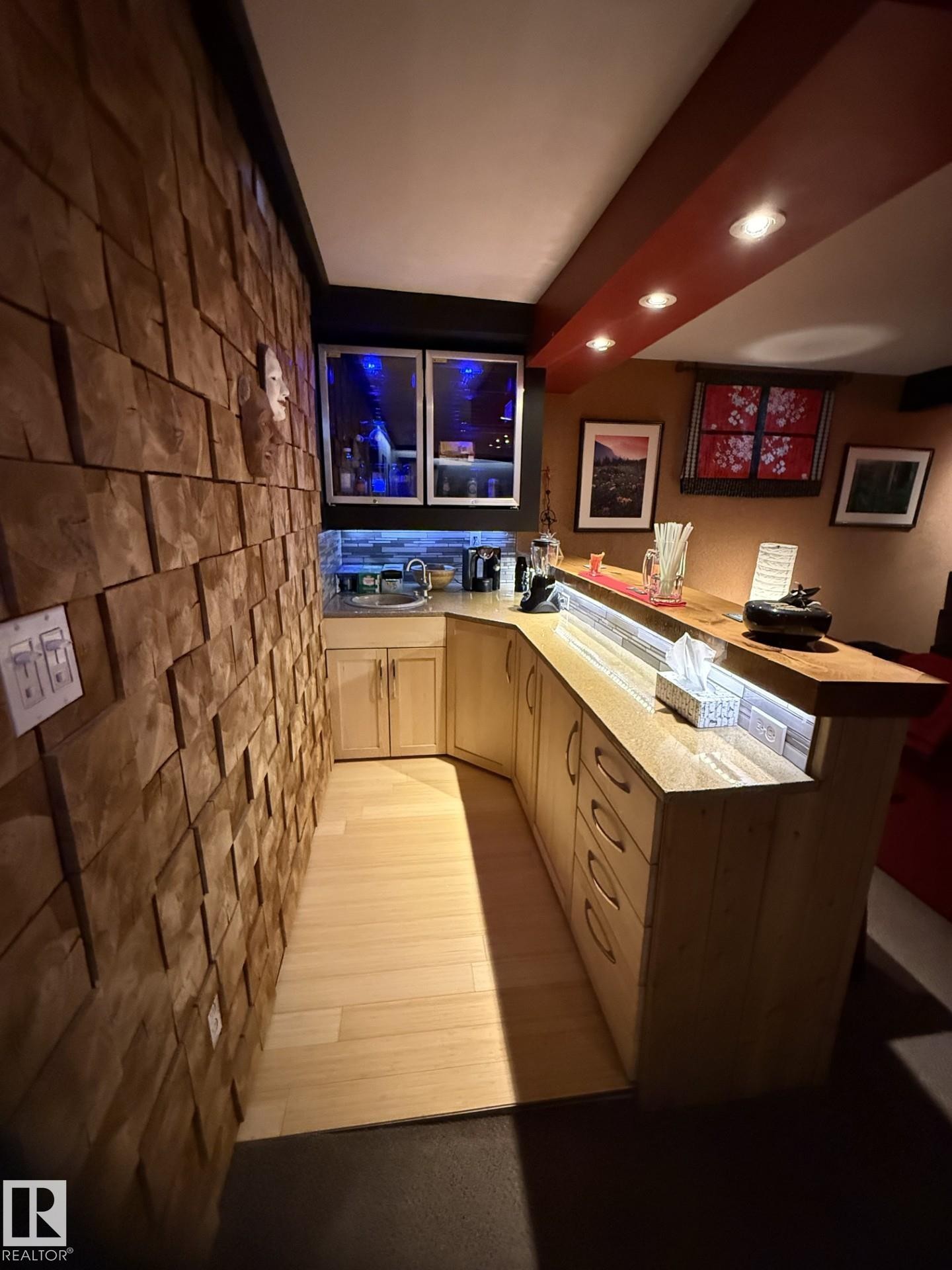 Custom wet bar featuring wood-finish cabinetry, a built-in sink, and illuminated glass-front upper cabinets - 9602 85 Street, Edmonton, AB